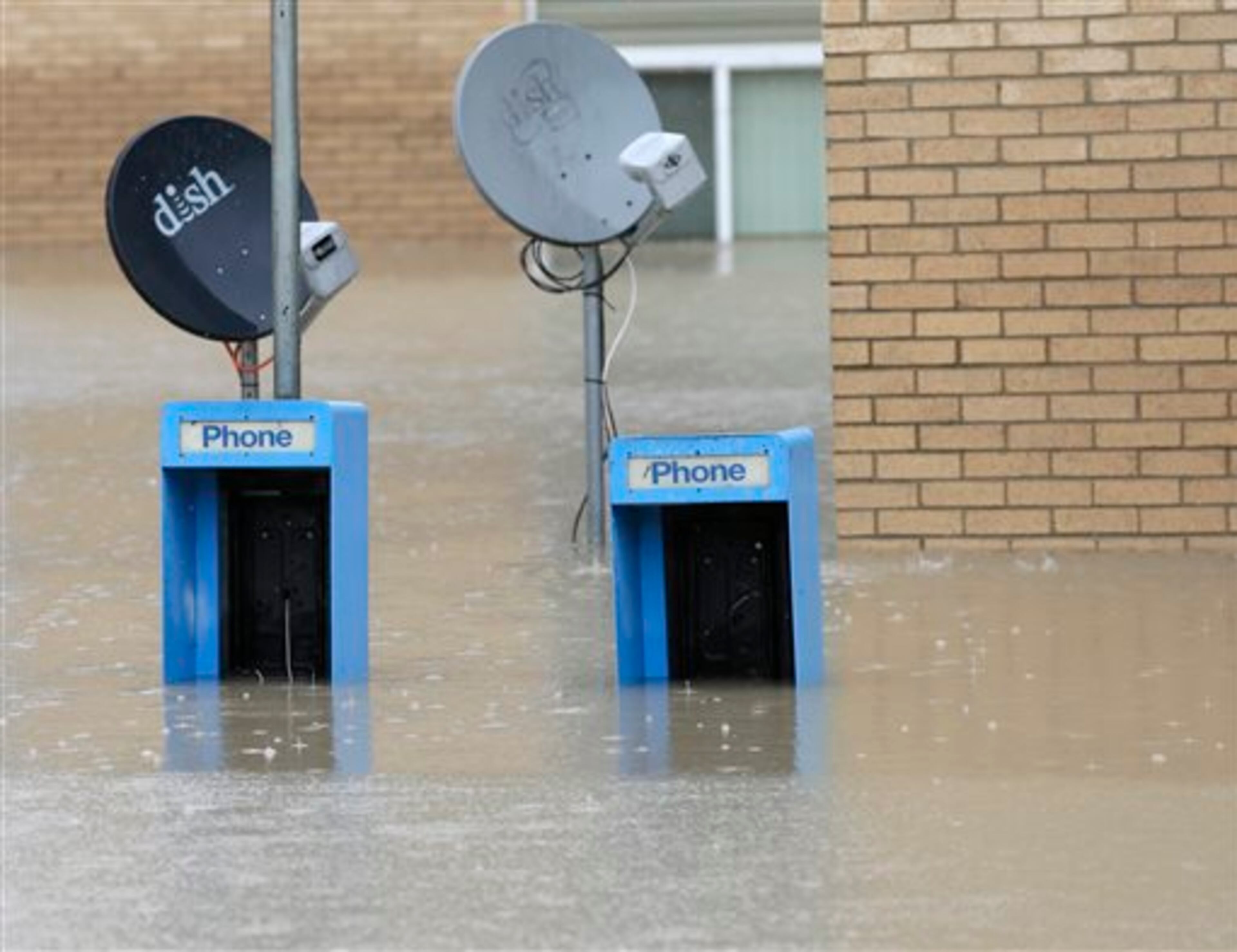 Satellite dishes and old pay telephones are shown in the parking lot of a flooded apartment building in Columbia, S.C., Sunday, Oct. 4, 2015. The rainstorm drenching the U.S. East Coast brought more misery Sunday to South Carolina, cutting power to thousands, forcing hundreds of water rescues and closing many roads because of floodwaters. (AP Photo/Chuck Burton)