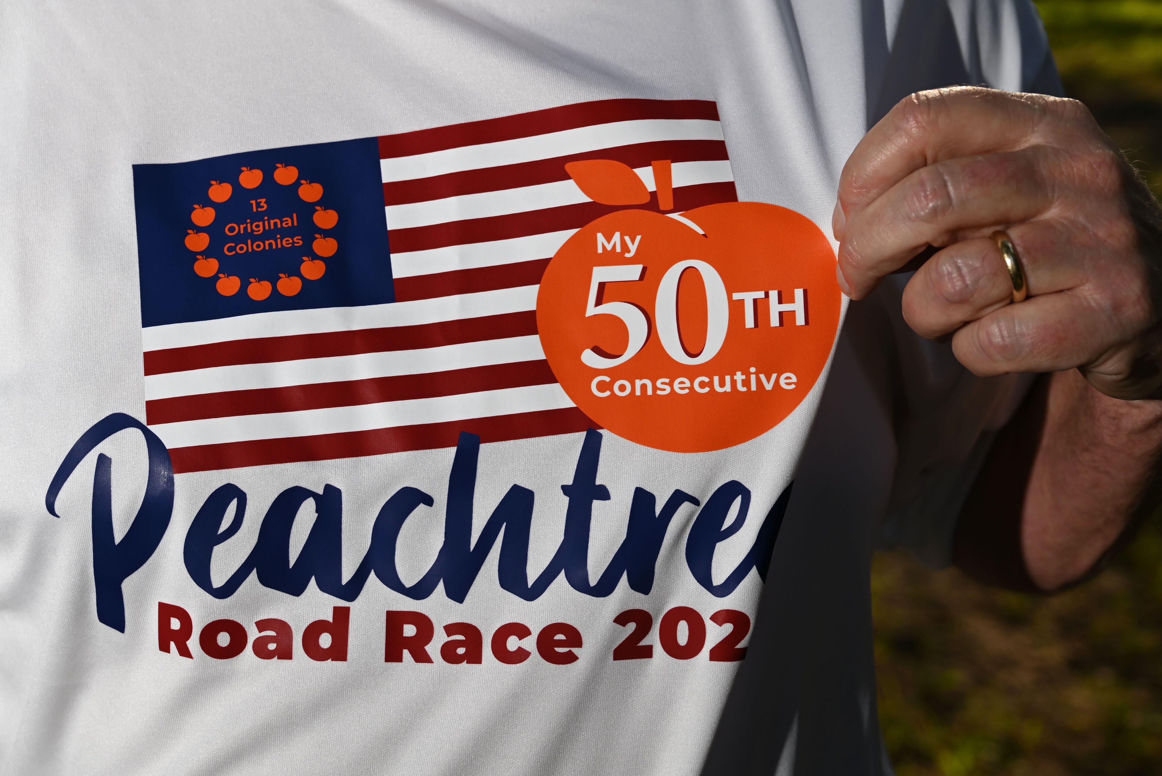 Greg Gates poses for a portrait wearing a custom-designed T-shirt to mark his 50th Peachtree Road Race. (Hyosub Shin/AJC)