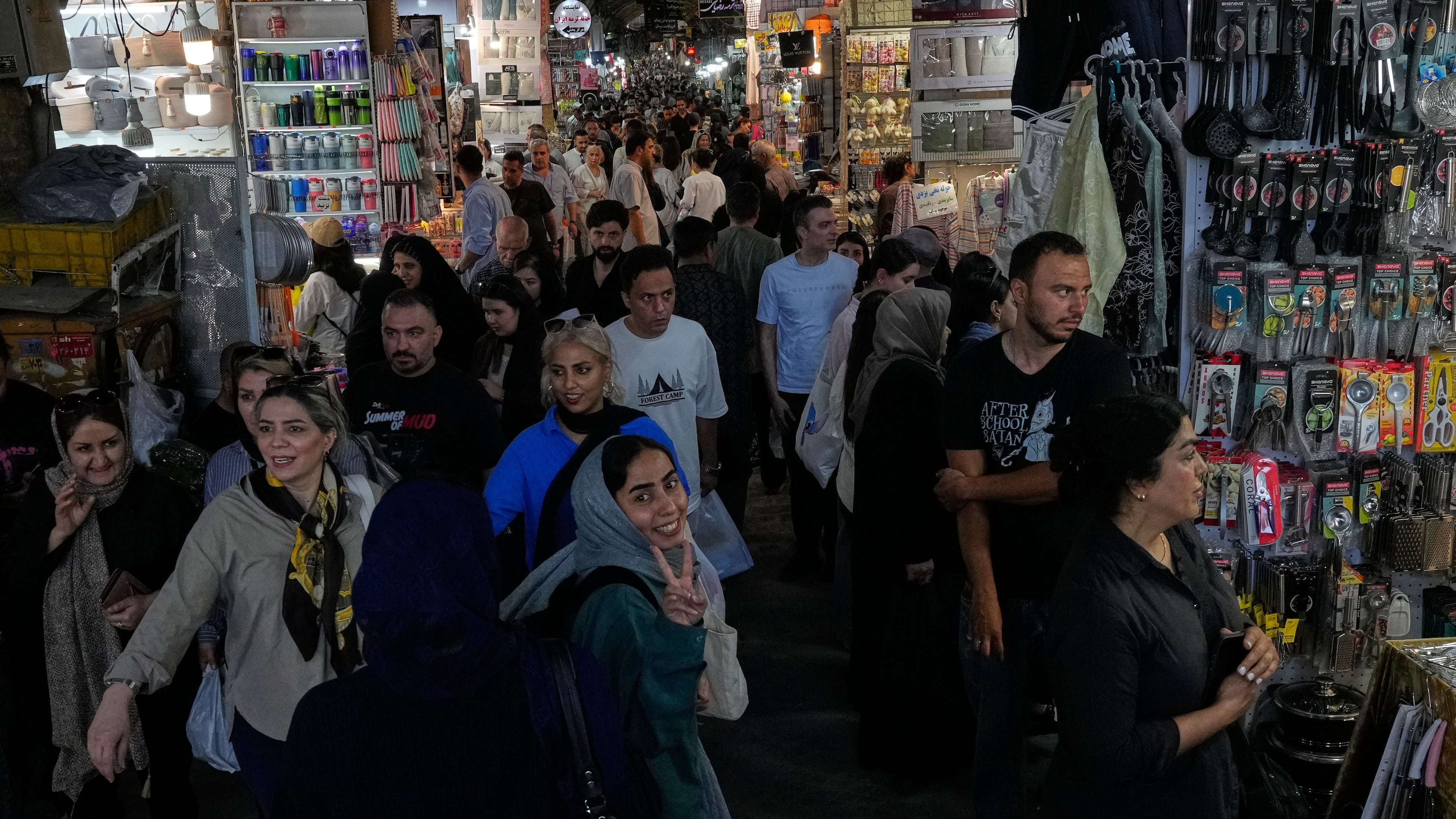 A woman flashes a victory sign while walking at Tehran's traditional main bazaar, Iran, Thursday, July 16, 2026. (AP Photo/Vahid Salemi)