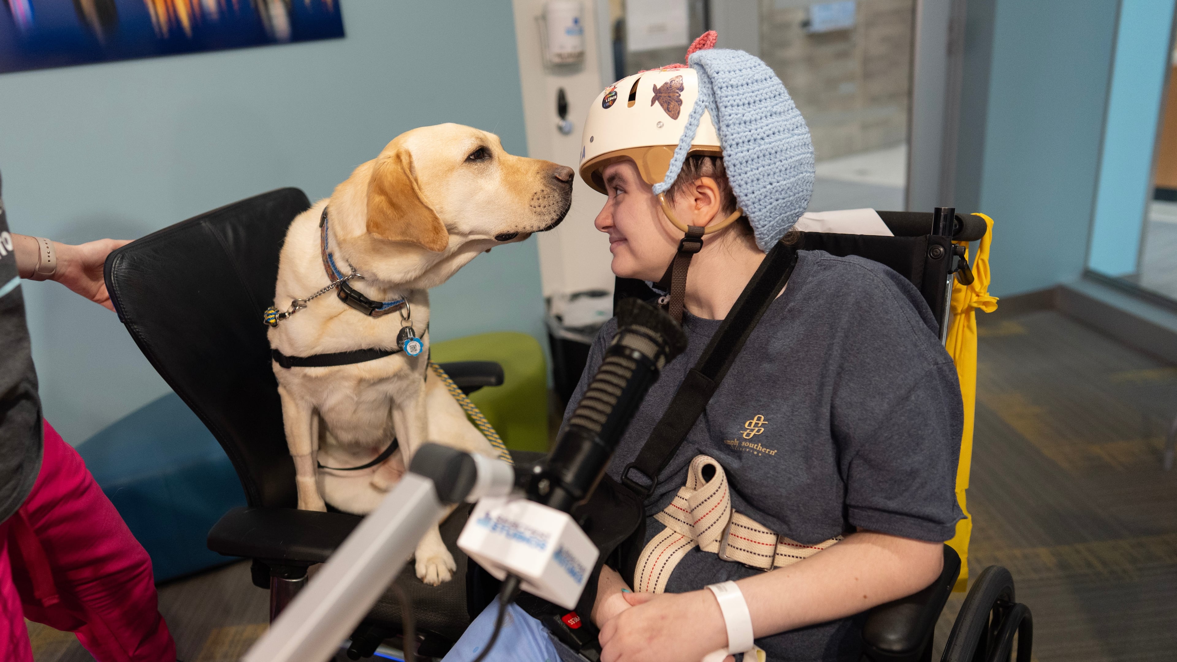Cincinnati Children's Hospital facility dog Grover, left, looks to patient Kira Hodge at the hospital's Seacrest Studios as they produce a closed-circuit television show beamed into patient rooms, at Cincinnati Children's Hospital in Cincinnati, Monday, May 4, 2026. (AP Photo/Carolyn Kaster)