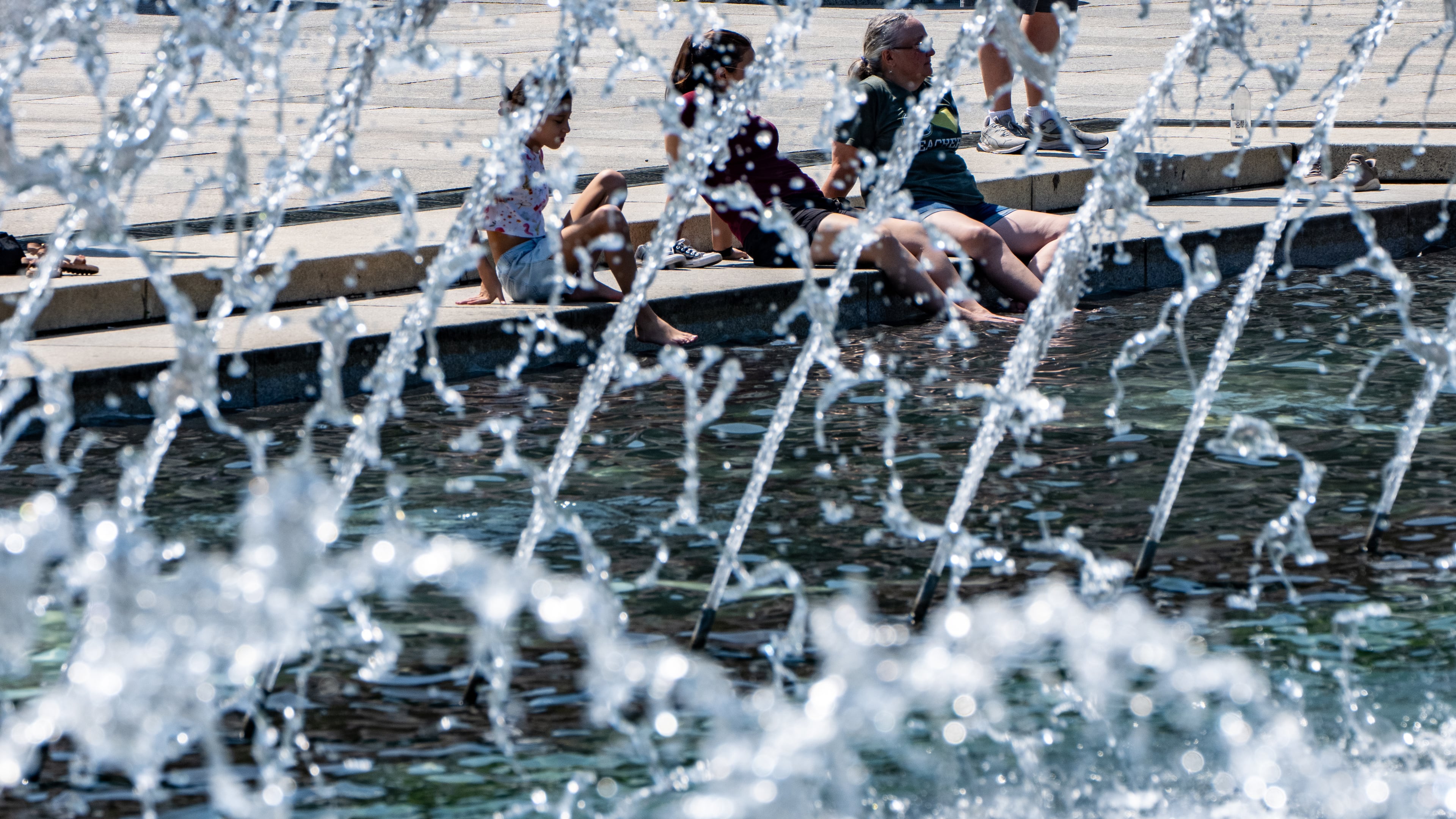 People cool their feet in the fountain at the WWII Memorial, Tuesday, June 30, 2026, in Washington. (AP Photo/Alex Brandon)