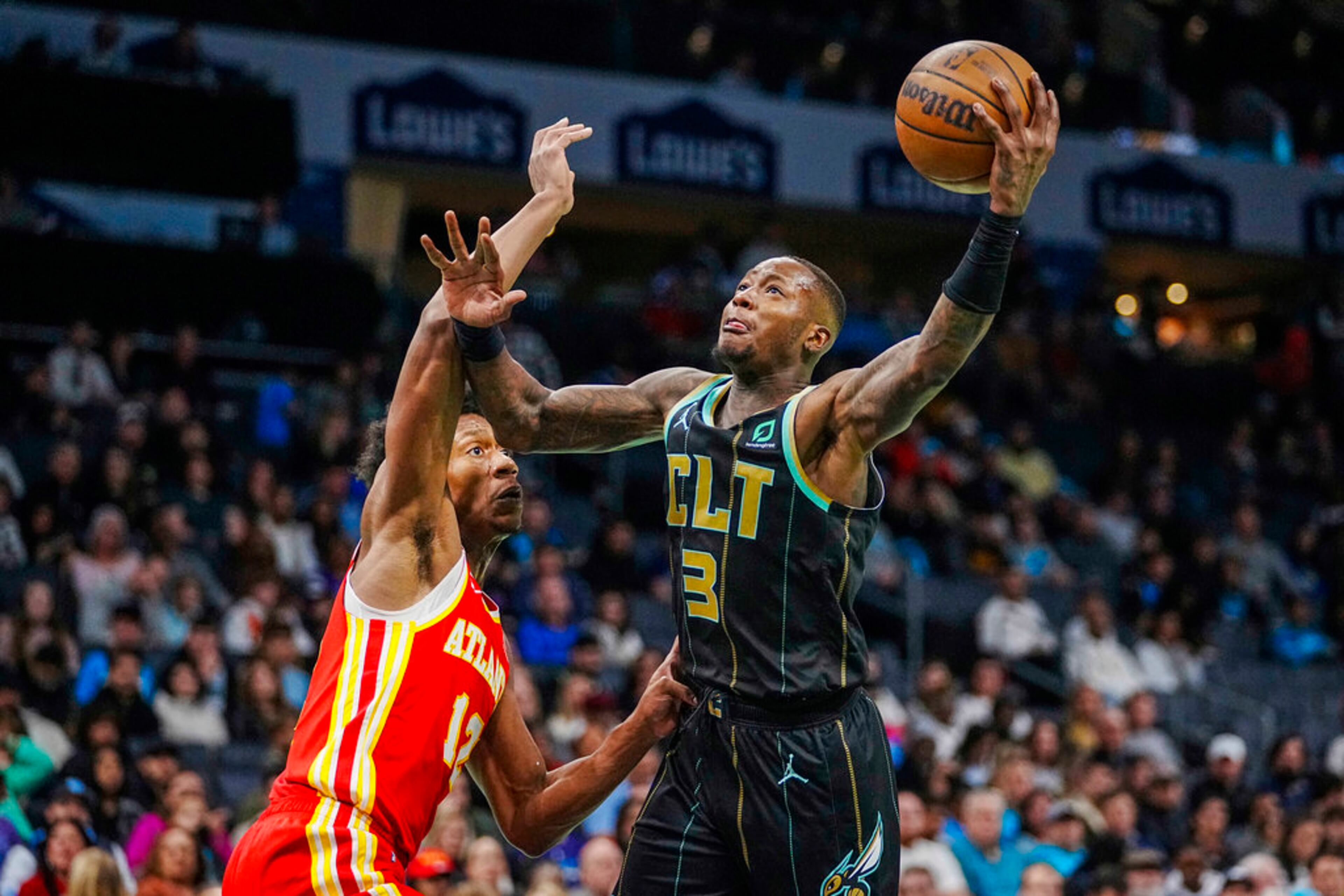 Charlotte Hornets guard Terry Rozier, right, drives into the lane against Atlanta Hawks forward De'Andre Hunter, left, during the first half of an NBA basketball game Friday, Dec. 16, 2022, in Charlotte, N.C. (AP Photo/Rusty Jones)