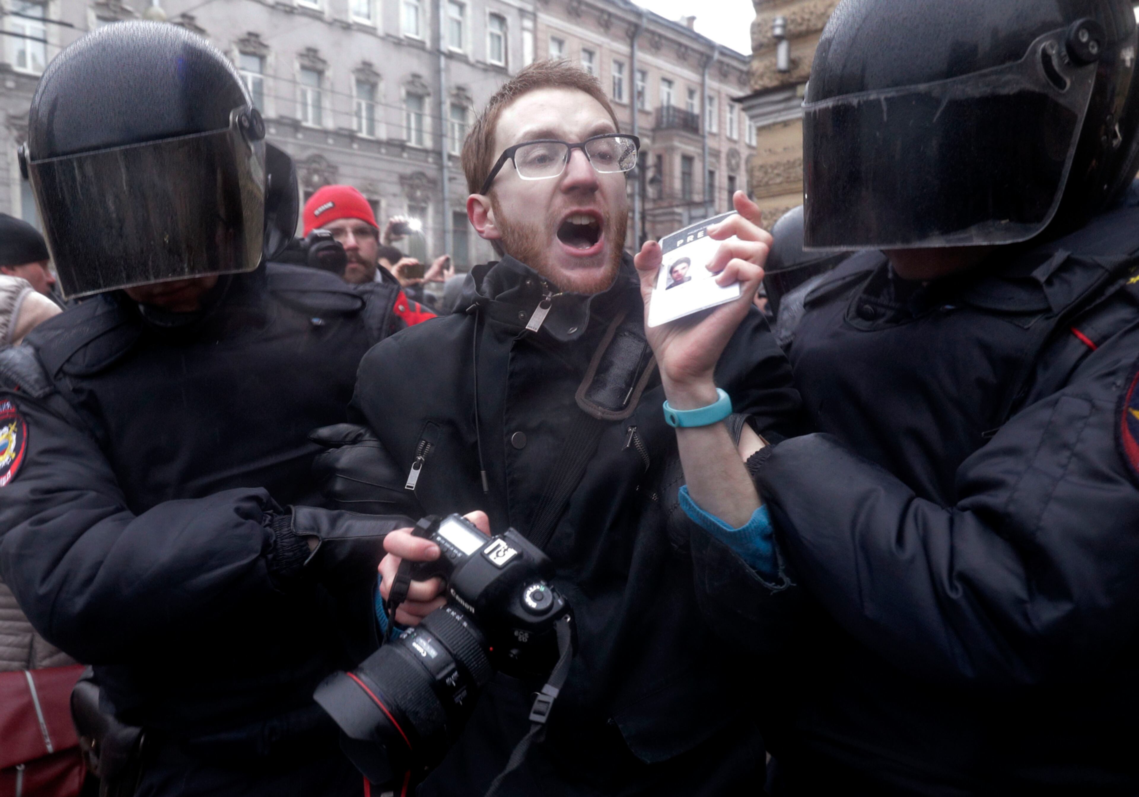 Riot policemen detain a journalist during a protest rally in St.Petersburg, Russia, Sunday, March 26, 2017. Thousands of people crowded in St.Petersburg on Sunday for an unsanctioned protest against the Russian government, the biggest gathering in a wave of nationwide protests that were the most extensive show of defiance in years. (AP Photo/Dmitri Lovetsky)