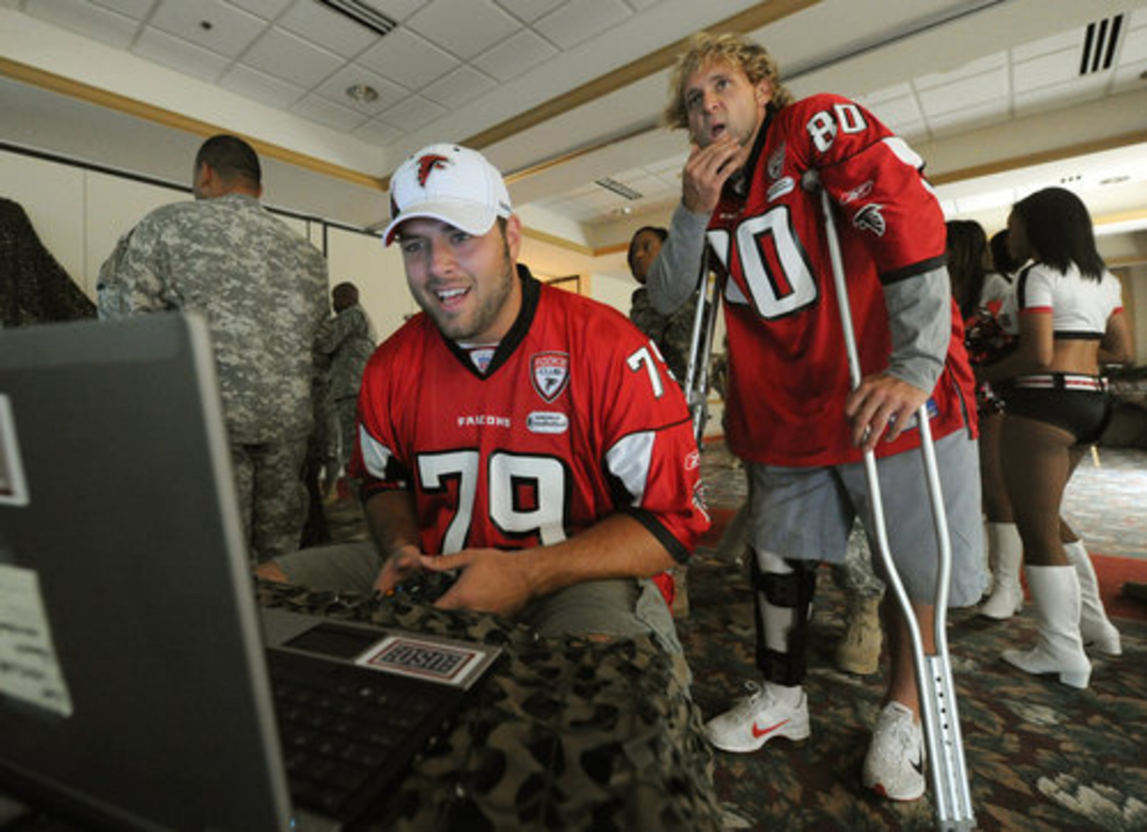 Atlanta Falcon Mike Johnson(79) plays video games with a soldier as Kerry Meier watches at Ft. McPherson on Tuesday, Sept 14,2010.
