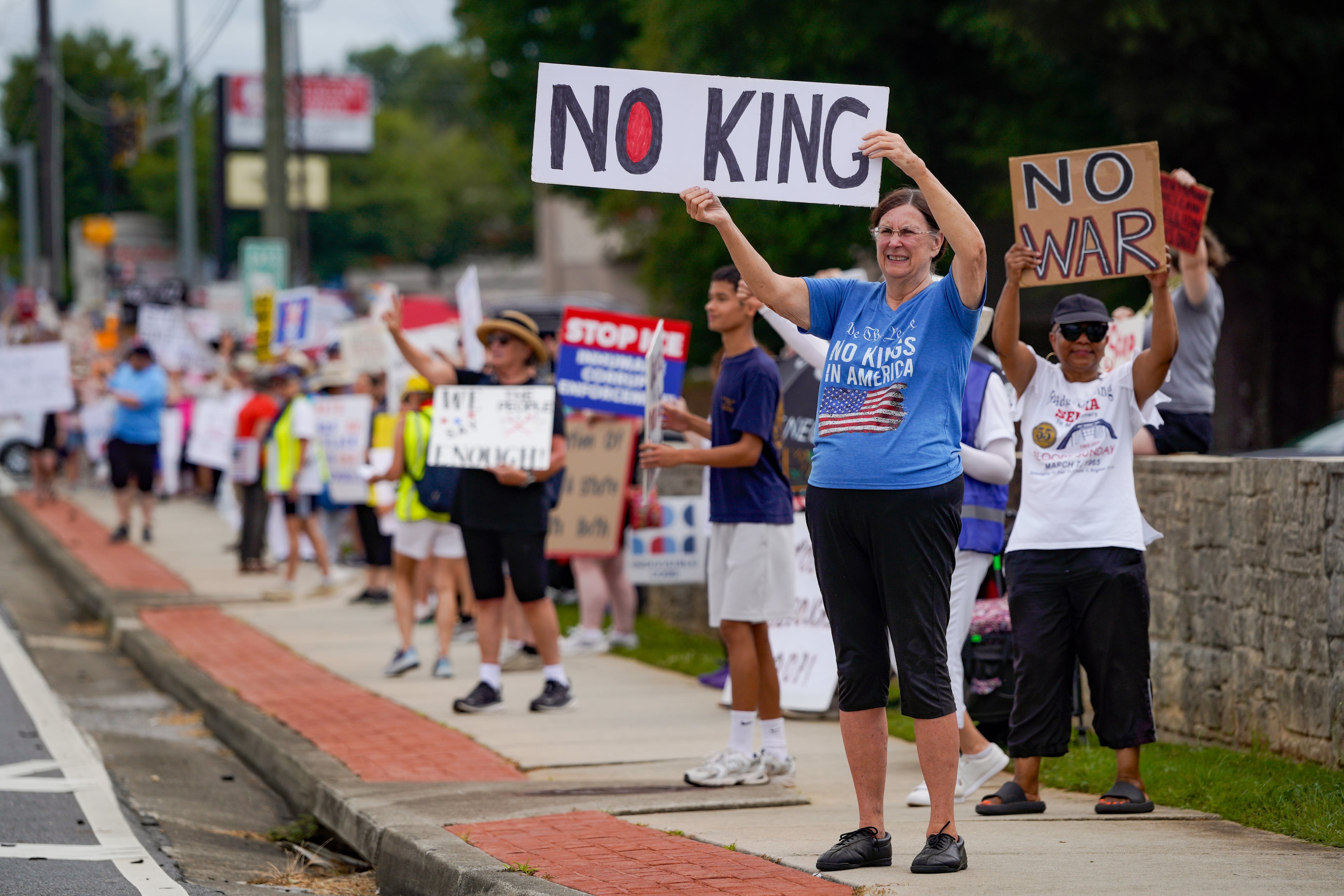 Protestors gather in Marietta while waiting for President Donald Trump to speak at Wheeler High School in Marietta on July 22, 2026. (Ben Hendren for the AJC)