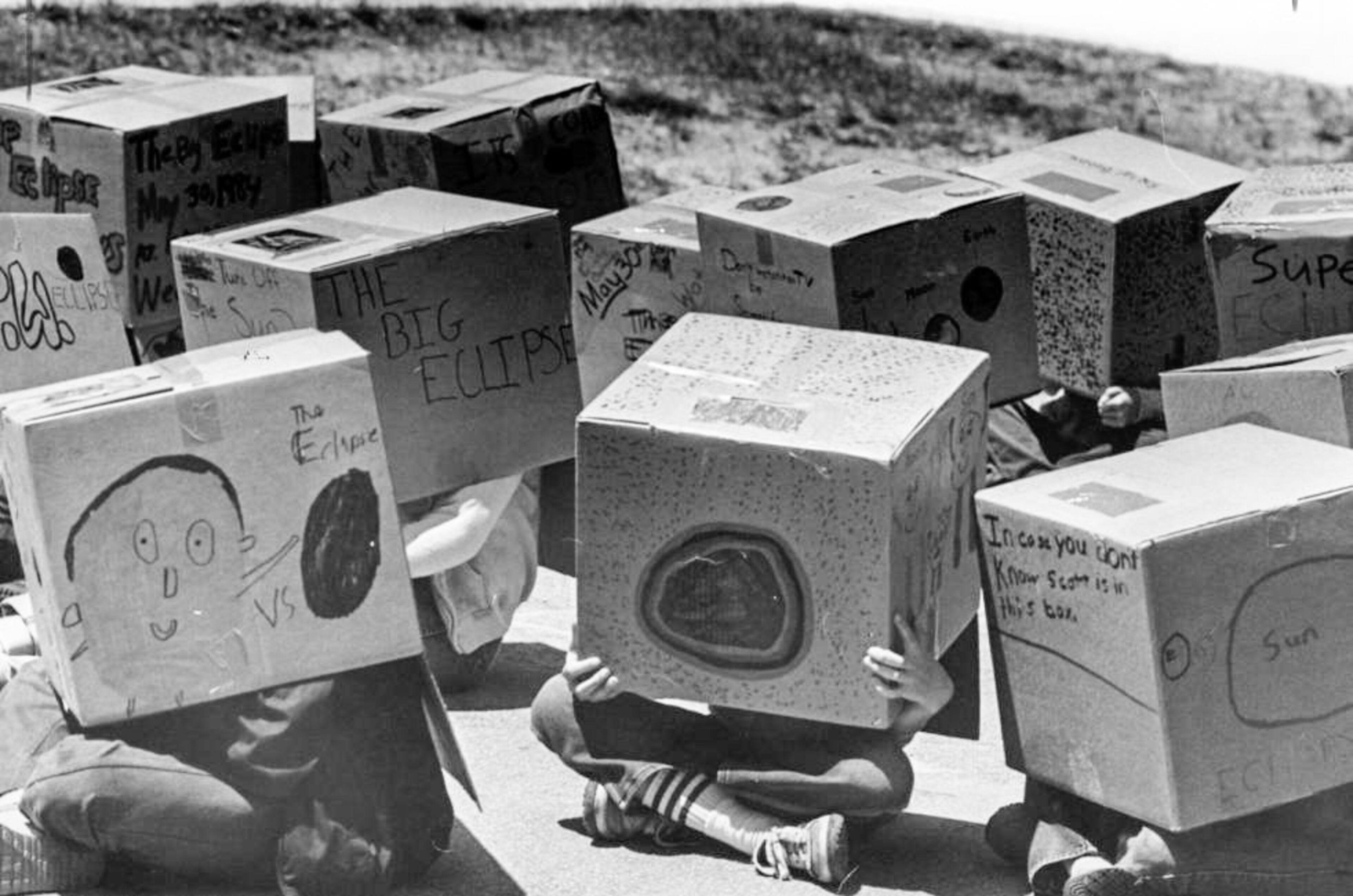Students at DeKalb County’s Forrest Hills Elementary School watch the solar eclipse safely through projection inside their homemade boxes on May 30, 1984.