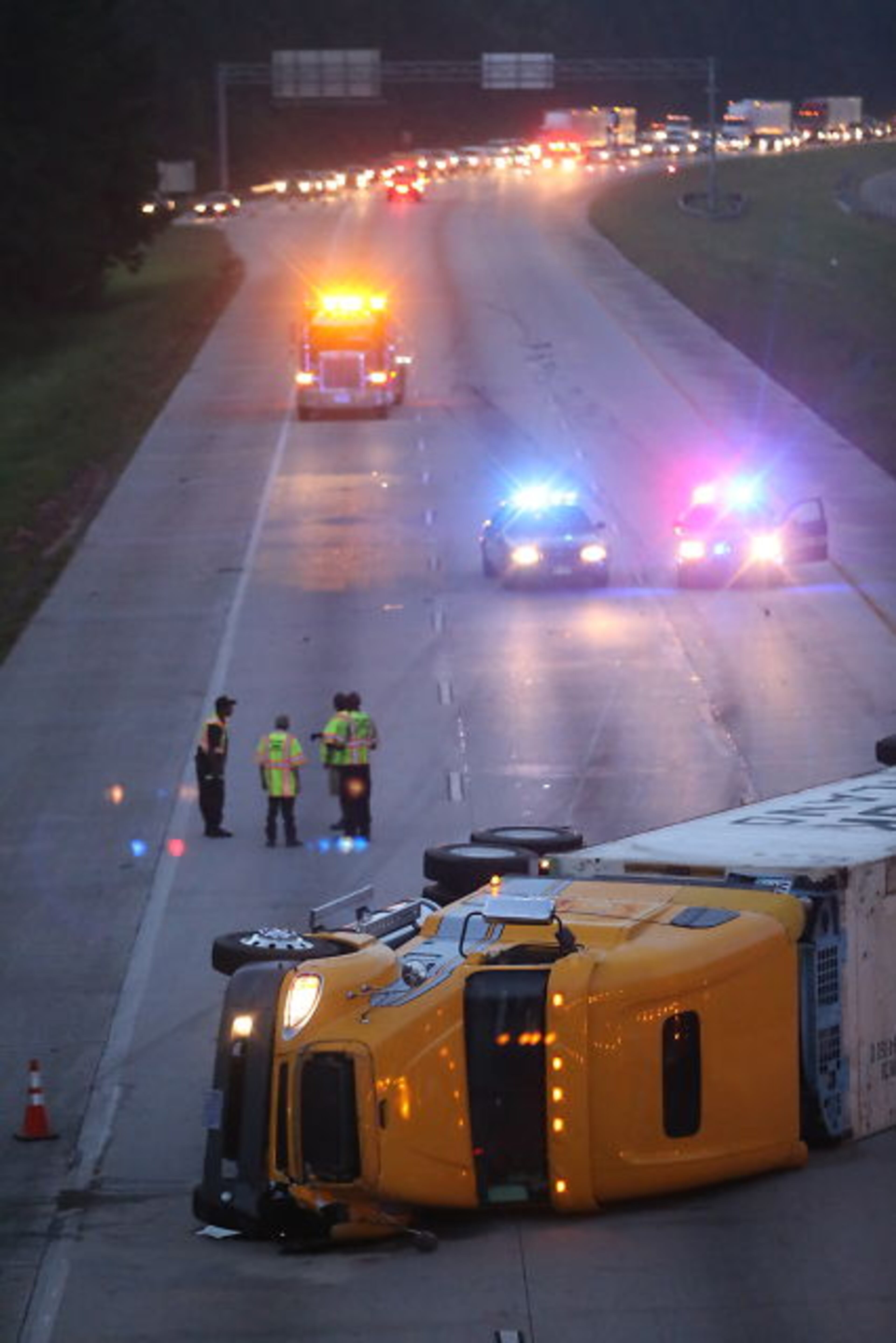 An overturned tractor-trailer shut down I-675 northbound in Clayton County during the early stages of the June 19 morning commute. JOHN SPINK / JSpink@ajc.com