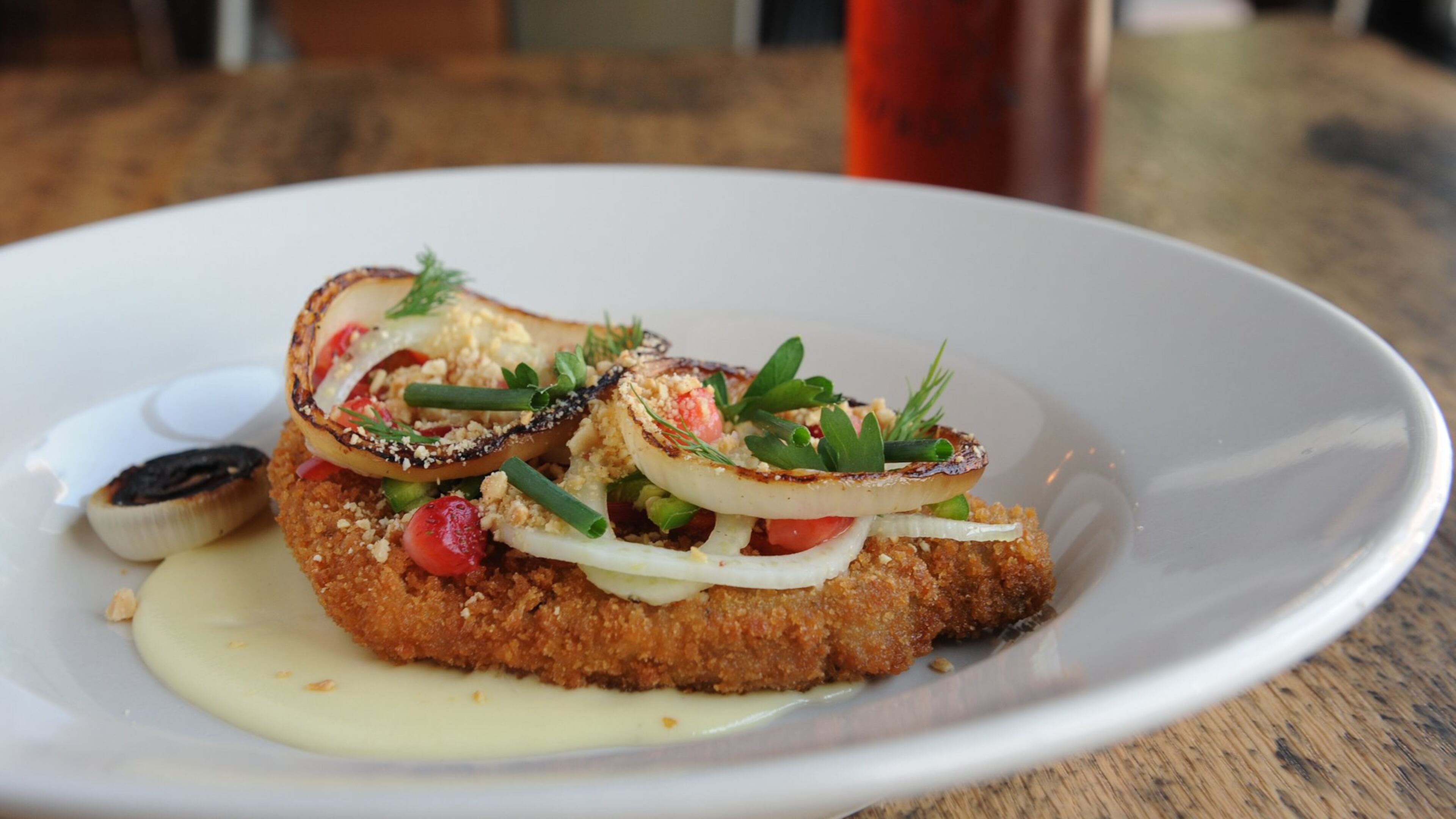 Pork loin schnitzel with “quickled” peaches and strawberries, jalapeno, charred sweet onion, peanuts, herbs and Gouda fonduta pictured with a Gate City Copperhead amber ale. (BECKY STEIN PHOTOGRAPHY)