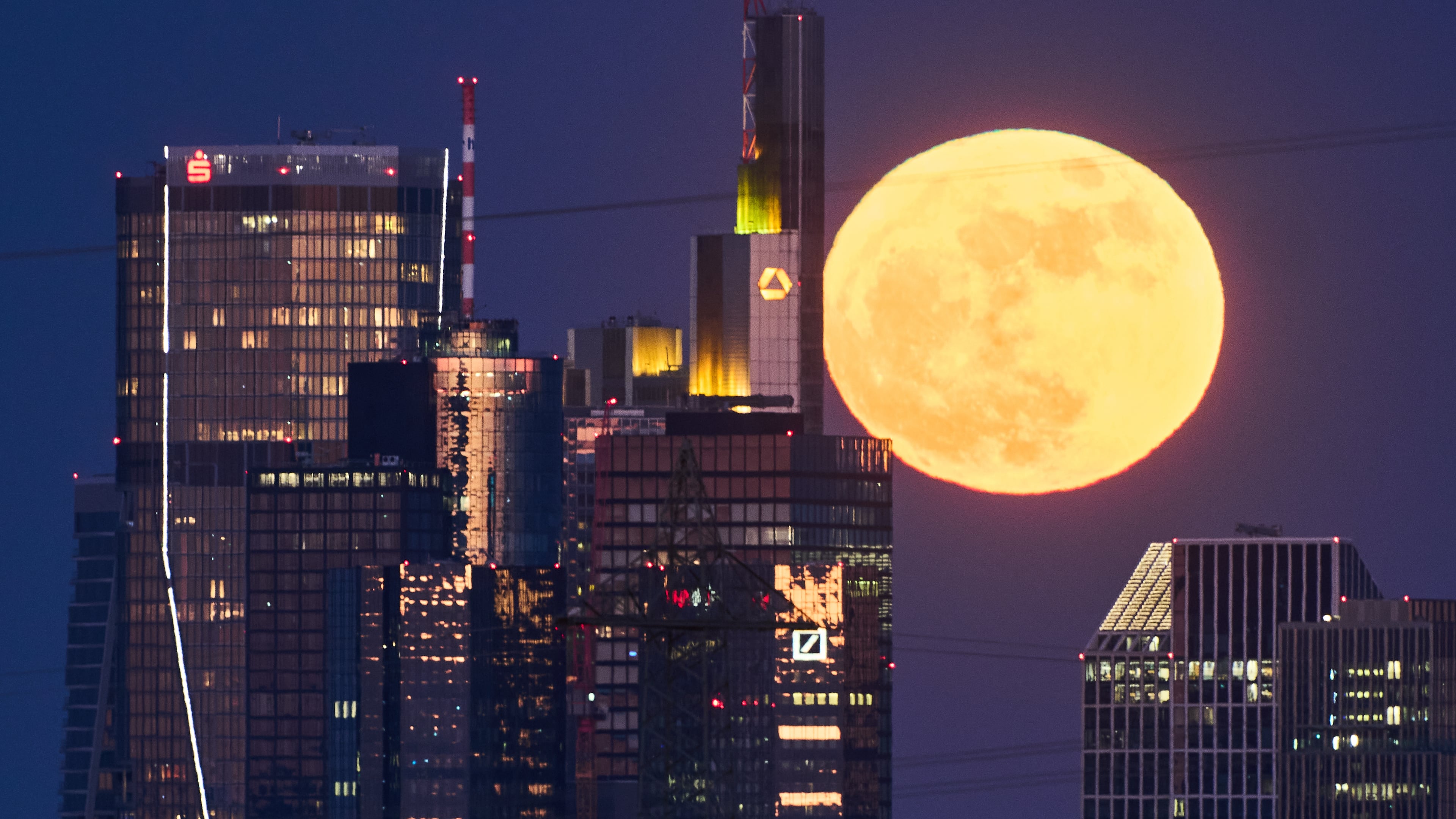 The full moon rises behind the buildings of the banking district in Frankfurt, Germany, Friday, May 1, 2026. (AP Photo/Michael Probst)