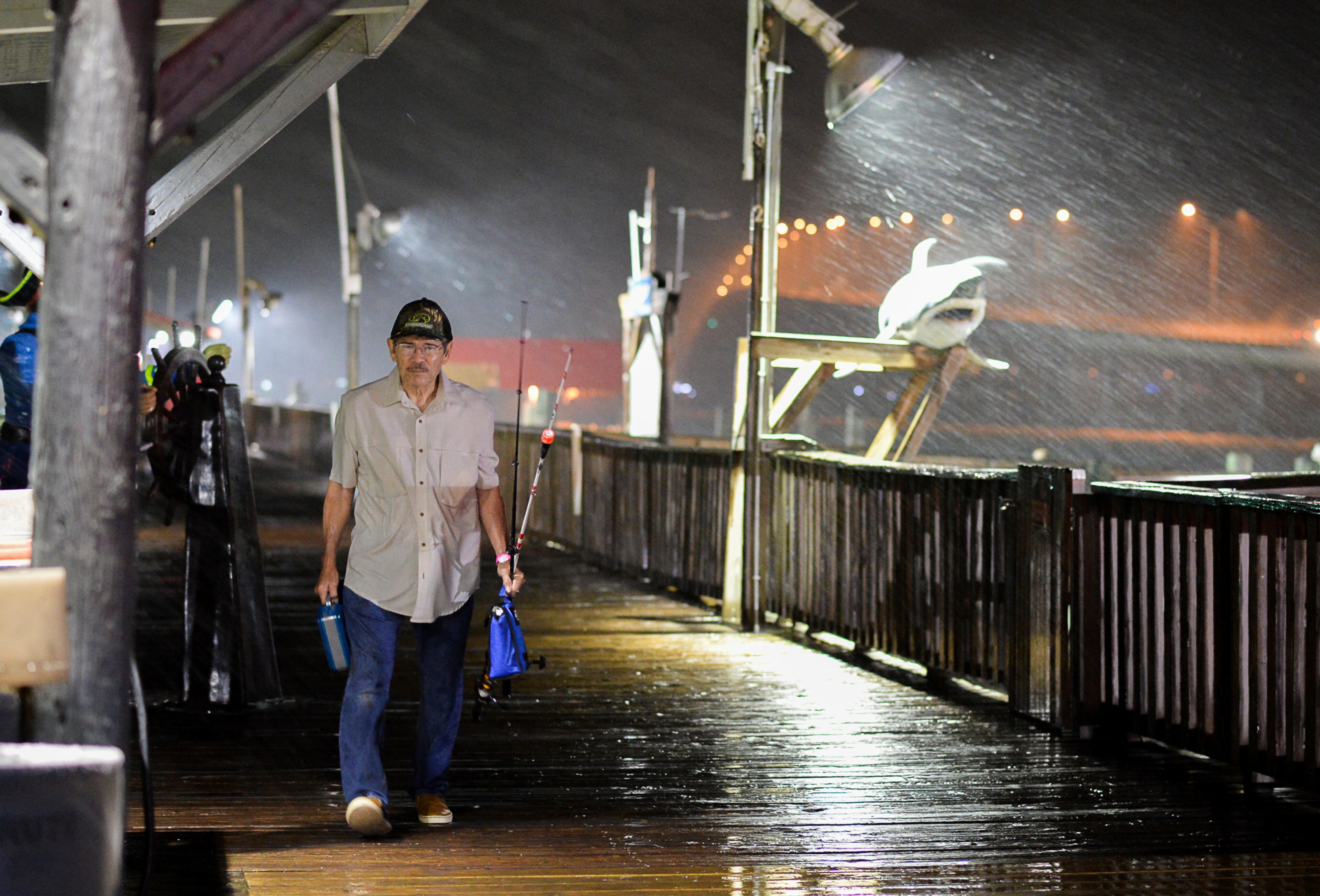 Rogelio Ortiz makes his way off the Pirate's Landing Fishing Pier as rain from Hurricane Harvey falls on Thursday, Aug. 24, 2017, in Port Isabel, Texas. Pier employees stated that the pier would be closed until further notice when the last few fishing customers departed. (Jason Hoekema/The Brownsville Herald via AP)