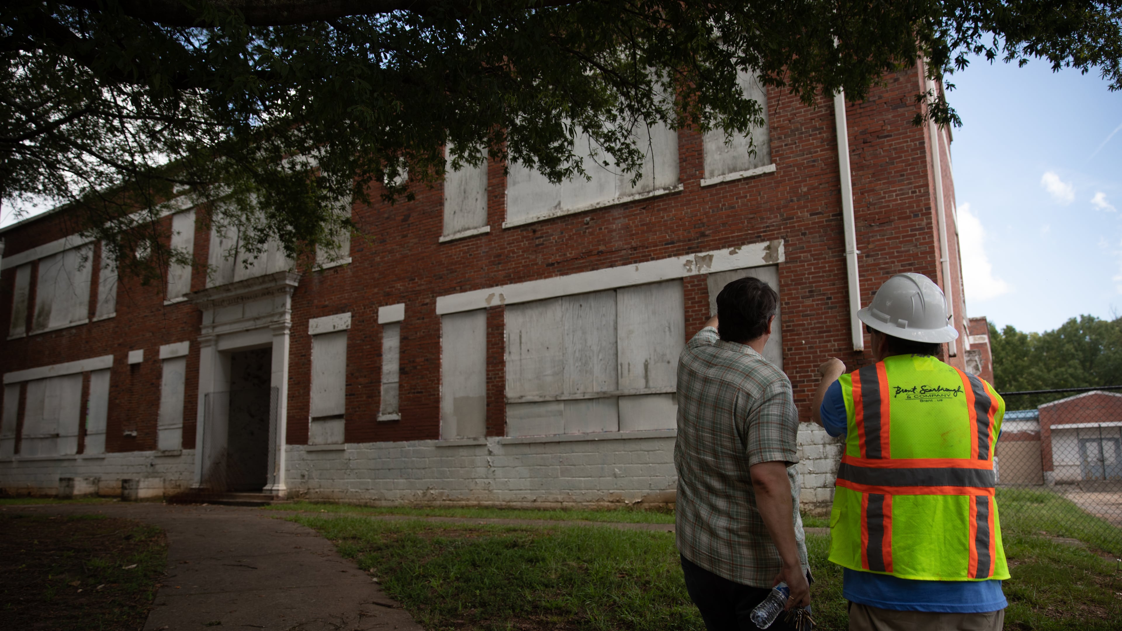 David Mitchell, executive director of the Atlanta Preservation Center (left) joins developers on a tour of the former Lakewood Elementary School, on July 17, 2025. The school is going to be revamped into a mixed-use space with retail and affordable housing units. (Riley Bunch/AJC)