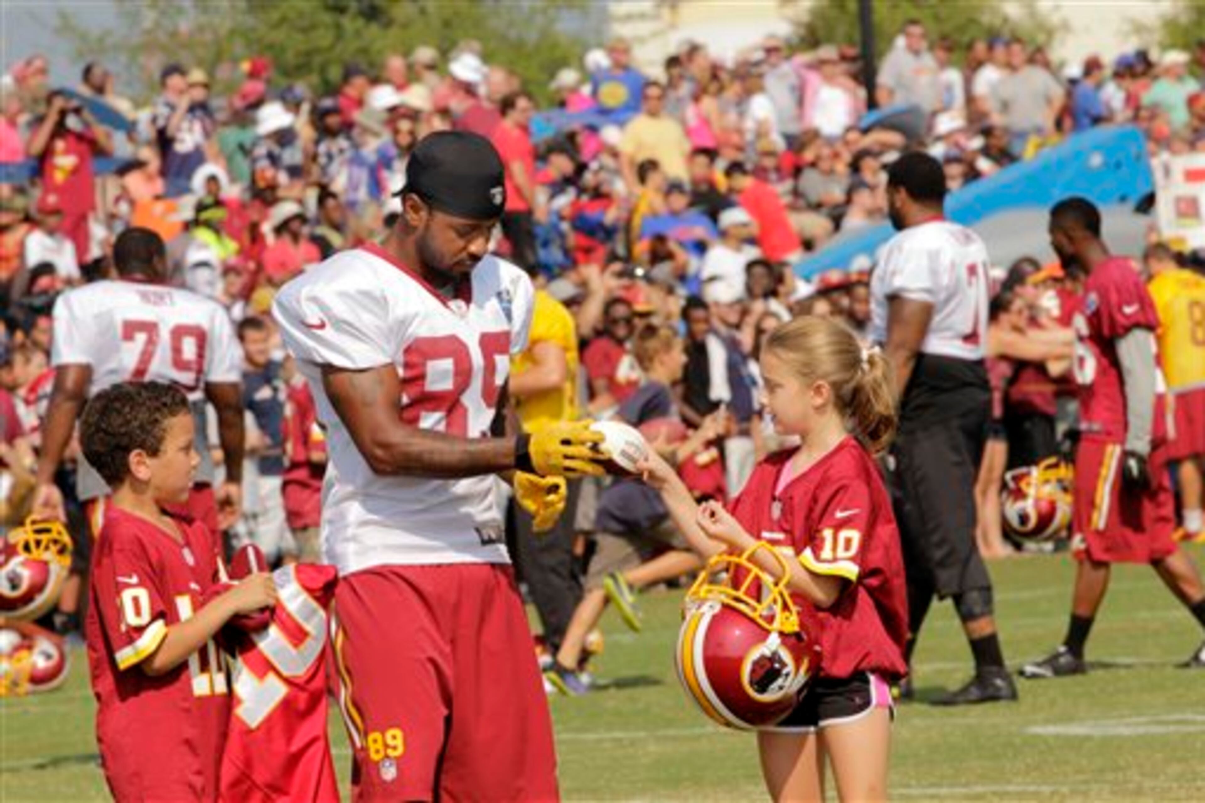 Washington Redskins NFL football team's Santana Moss (89) signs autographs with Kaya Todd, 9, right, and Devin Wright, 7, after a joint practice with he New England Patriots in Richmond, Va., Wednesday, Aug. 6, 2014. (AP Photo/Jay Paul)