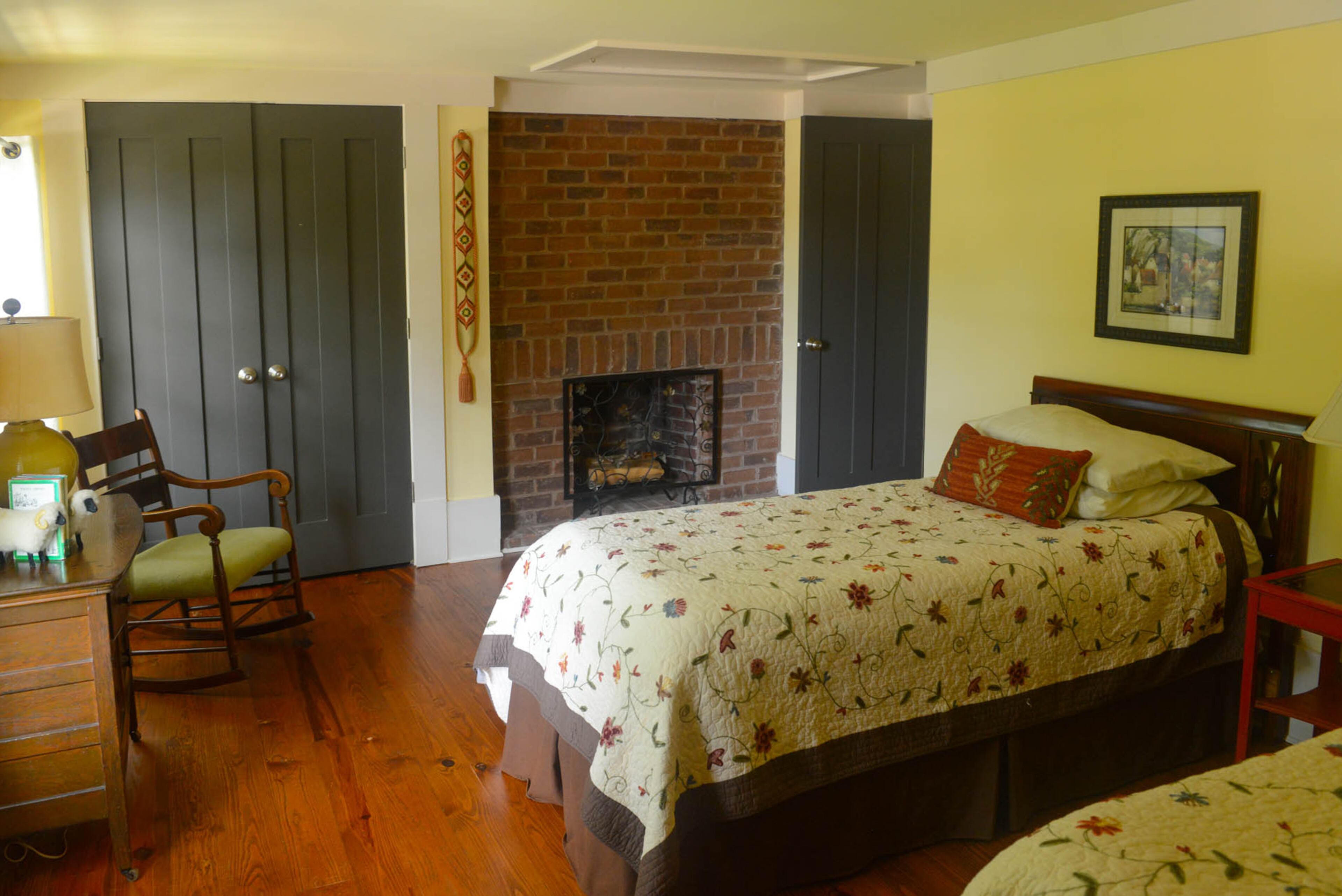 One of four bedrooms in the home, the upstairs guestroom houses two twin beds and another fireplace. Hanging next to the fireplace is a woven bell pull that was made by Dee's mother.