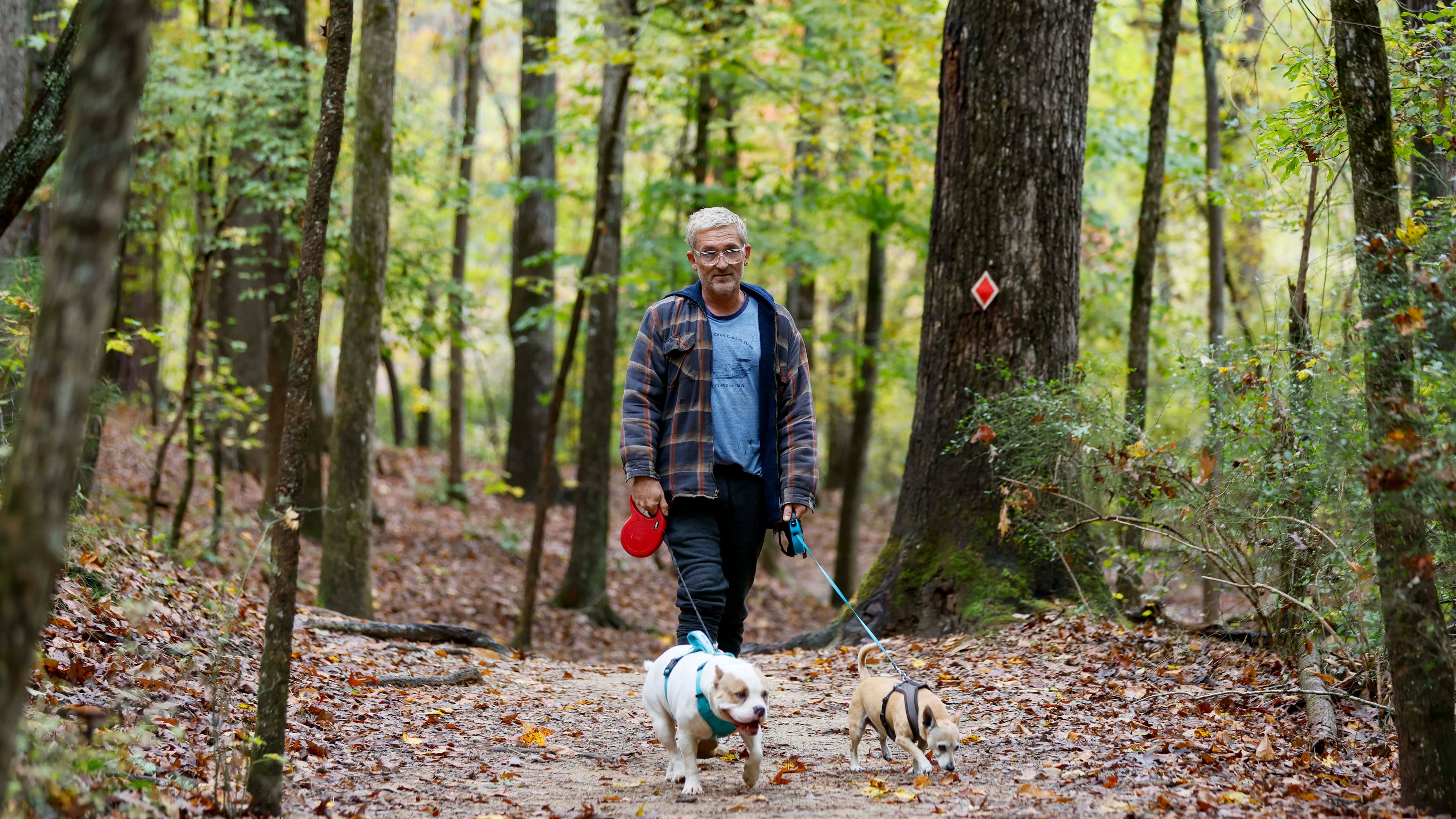 Terrance Wahl of Decatur takes a walk with his pets, Teddy and Tippi, along Sweet Water Creek in October 2025. (Miguel Martinez/AJC)