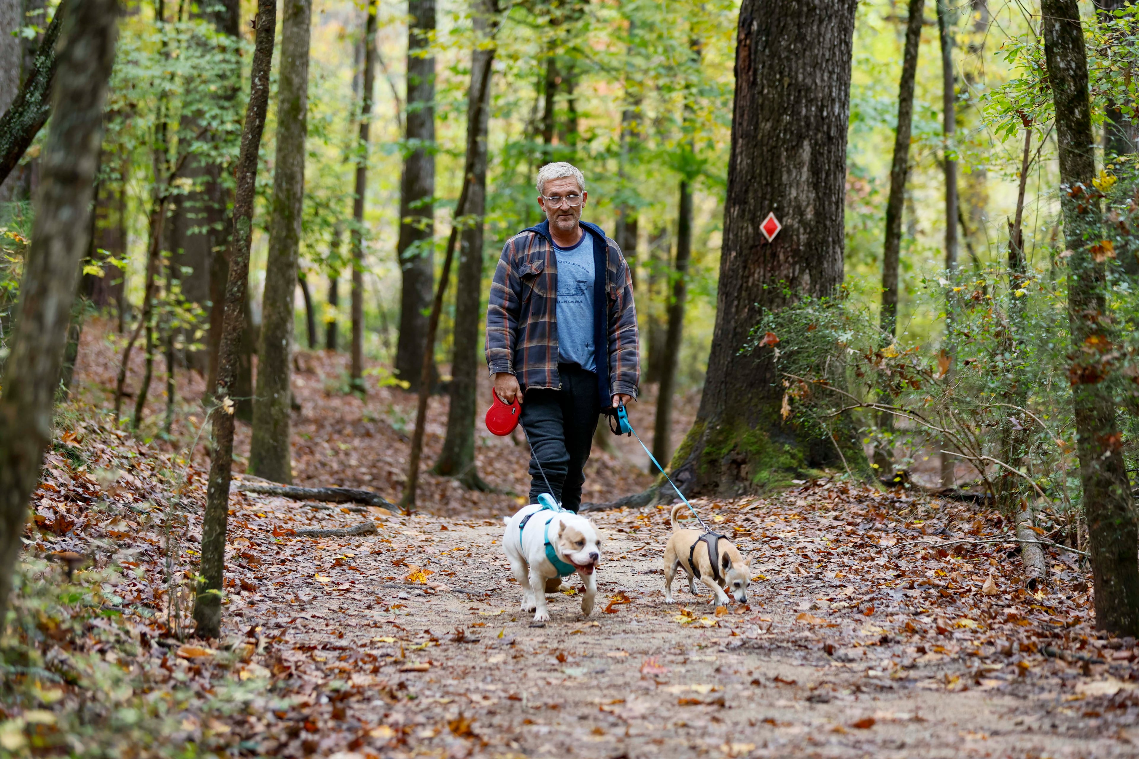 Terrance Wahl of Decatur takes a walk with his pets, Teddy and Tippi, along Sweet Water Creek in October 2025. (Miguel Martinez/AJC)