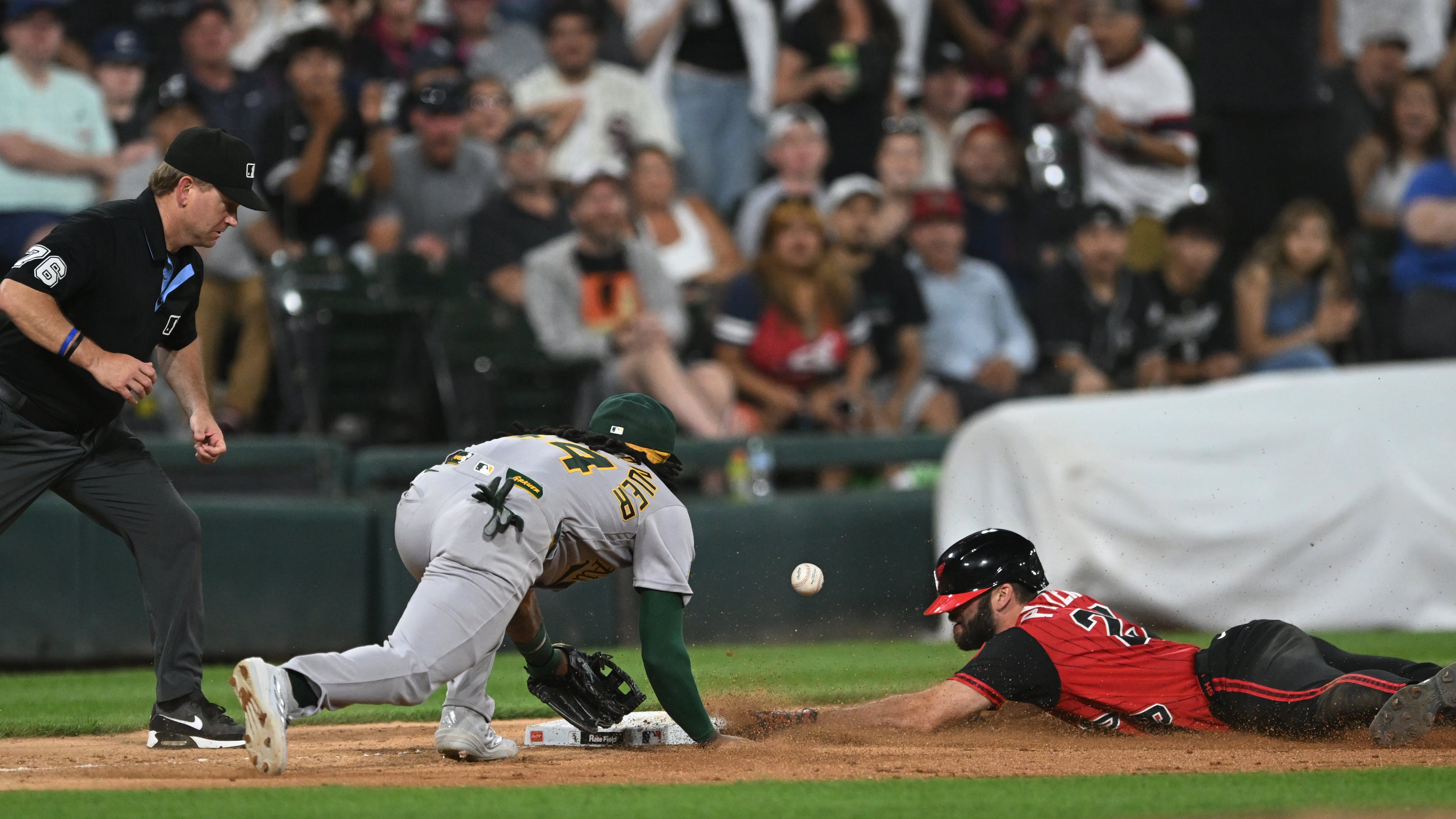 Chicago White Sox's Tristan Peters, right, slides safely into third base for an RBI triple while Athletics third baseman Joshua Kuroda-Grauer, center, catches the throw during the seventh inning of a baseball game in Chicago, Friday, July 10, 2026. (AP Photo/Paul Beaty)