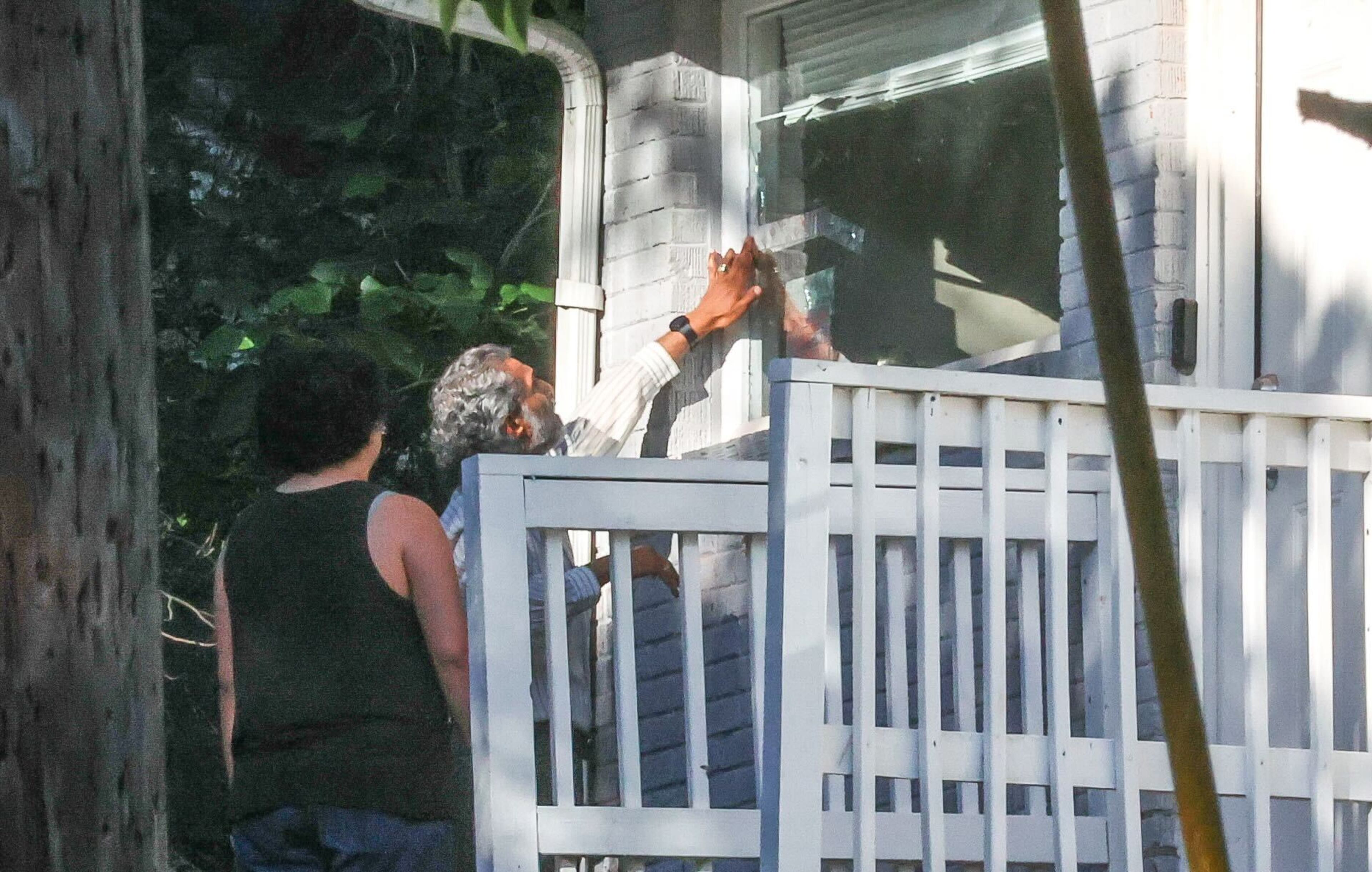 Neighbors are seen covering bullet holes after gunfire erupted in northwest Atlanta on Thursday morning.