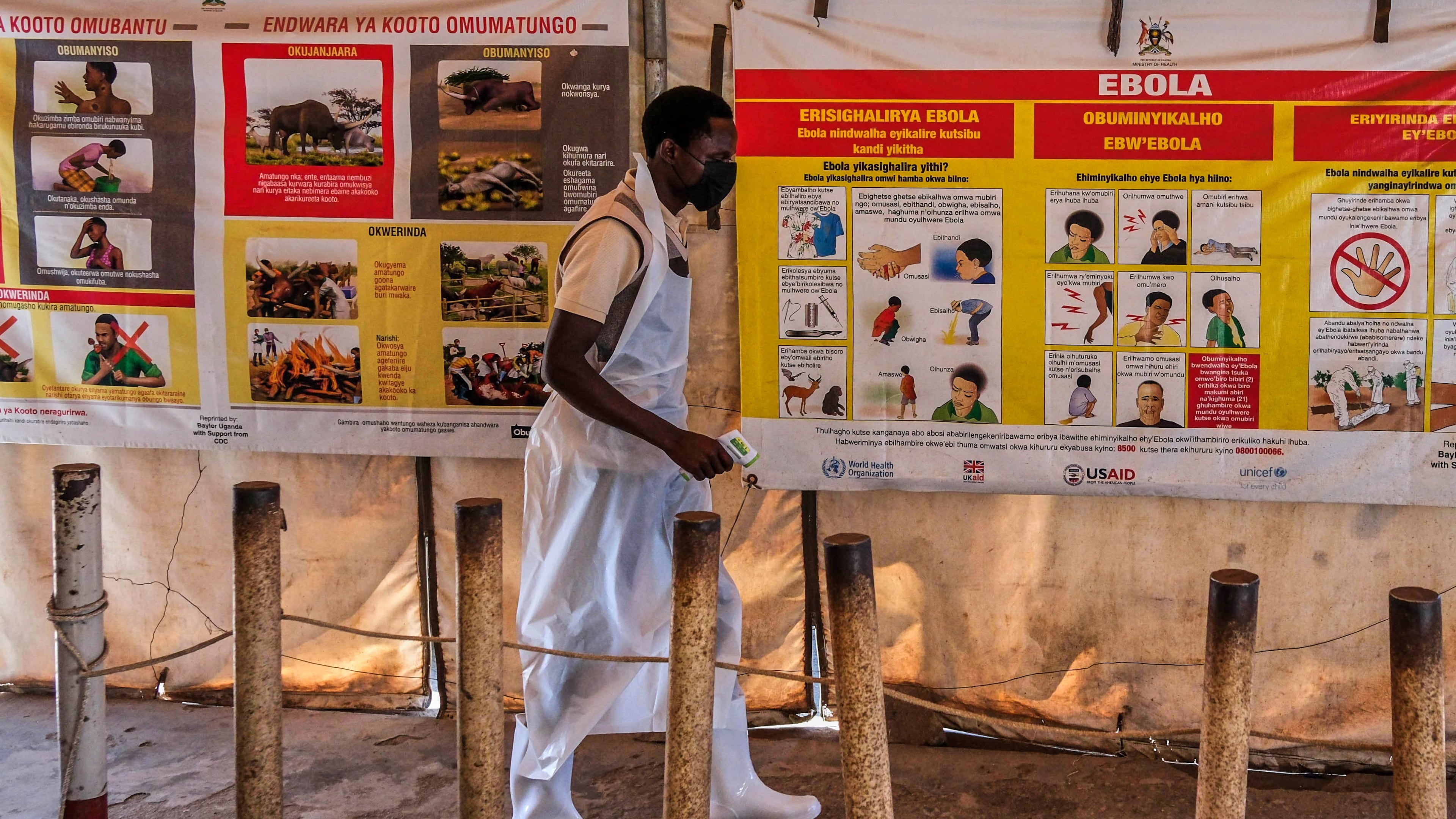 A health worker walks past Ebola warning and instruction posters at a temporary health clinic at the Mpondwe border crossing linking Uganda and the Democratic Republic of the Congo, Thursday, June 4, 2026. (AP Photo/Hajarah Nalwadda)