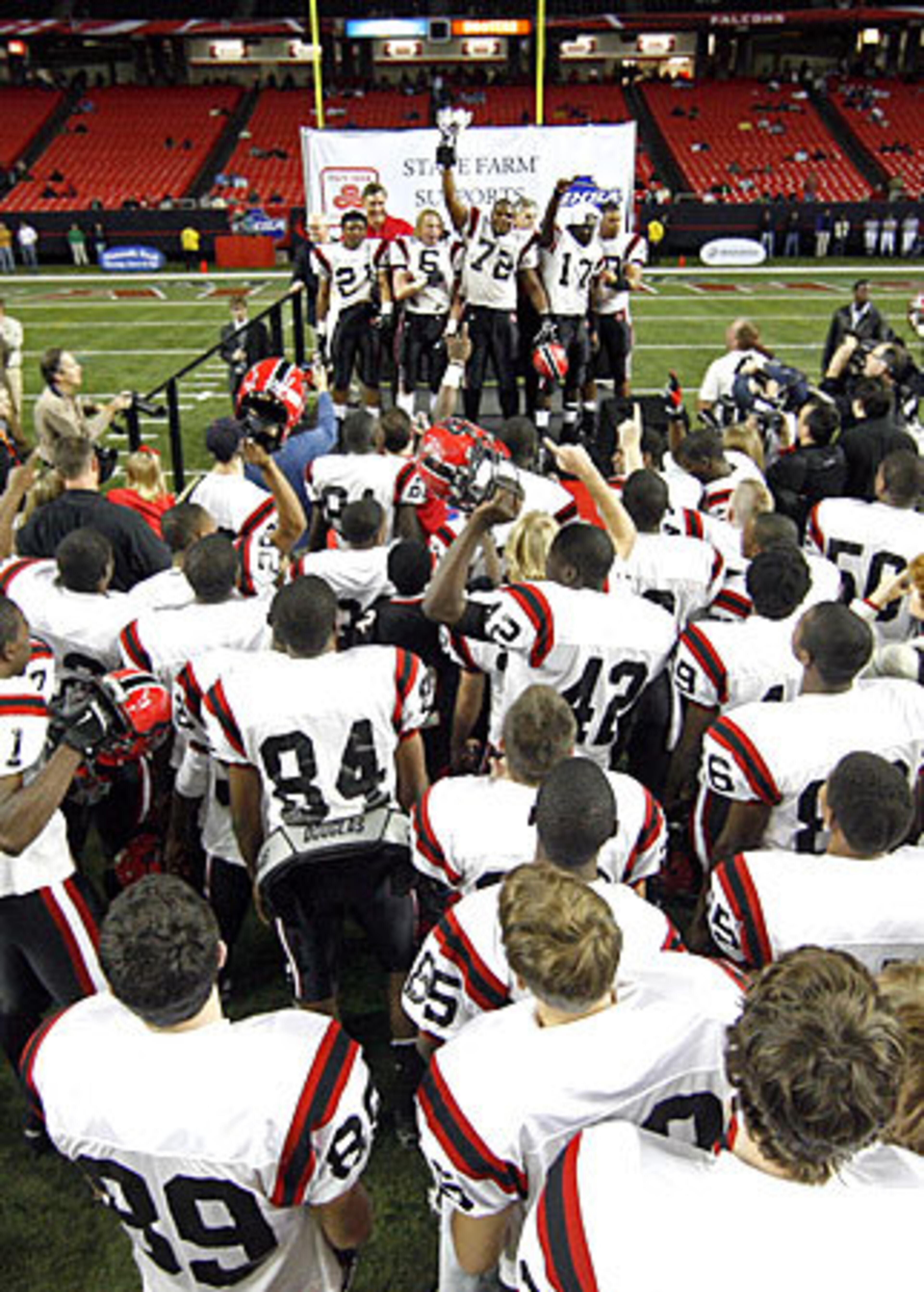 Cairo's Montavious Williams (72) holds up the Class AAA trophy as his teammates celebrate.