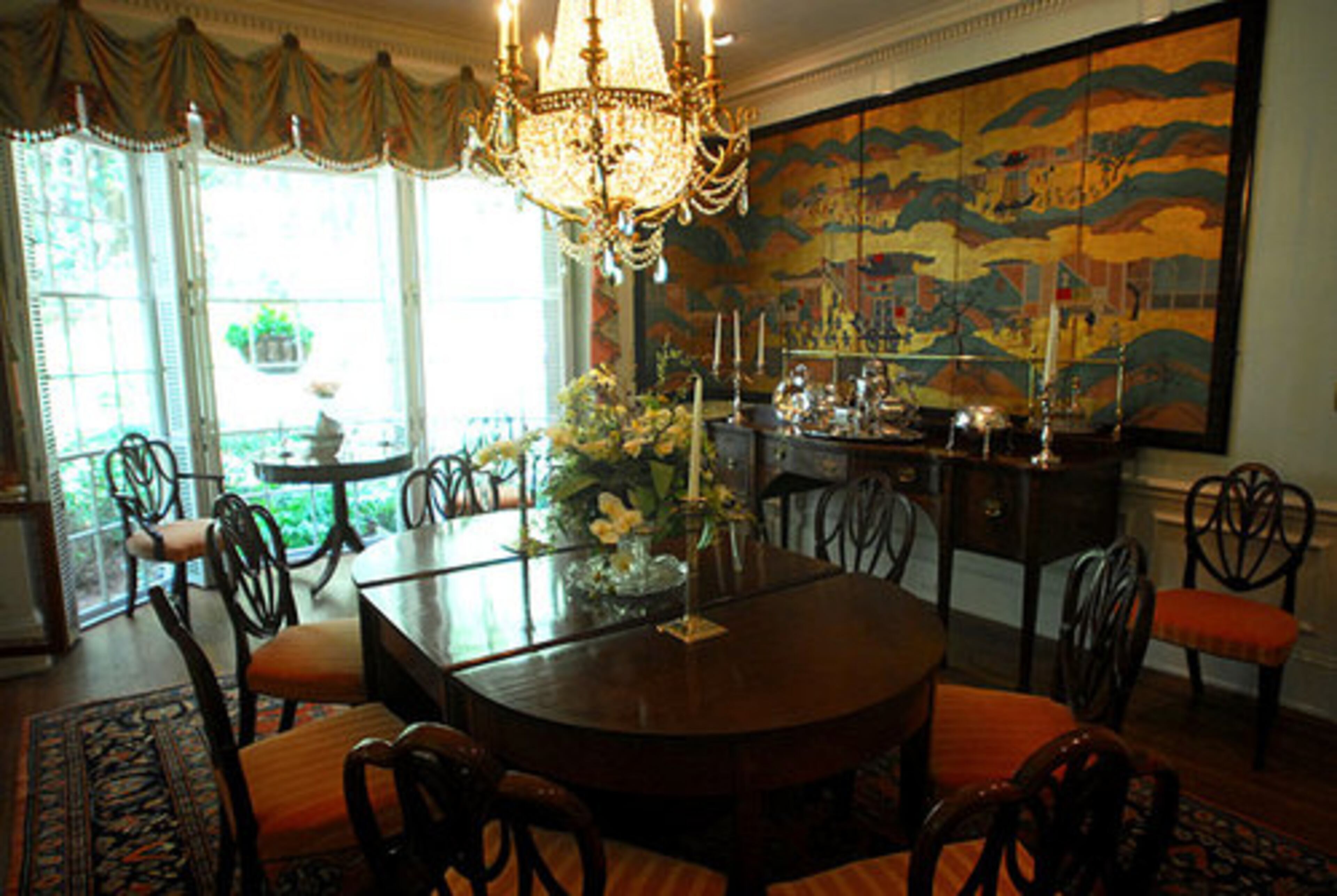The formal dining room features a crystal chandelier and two late-17th century Japanese screens depicting the annual Gion harvest festival in Kyoto. Anne Colgin acquired the screens from the estate of the late decorator David Byers.
