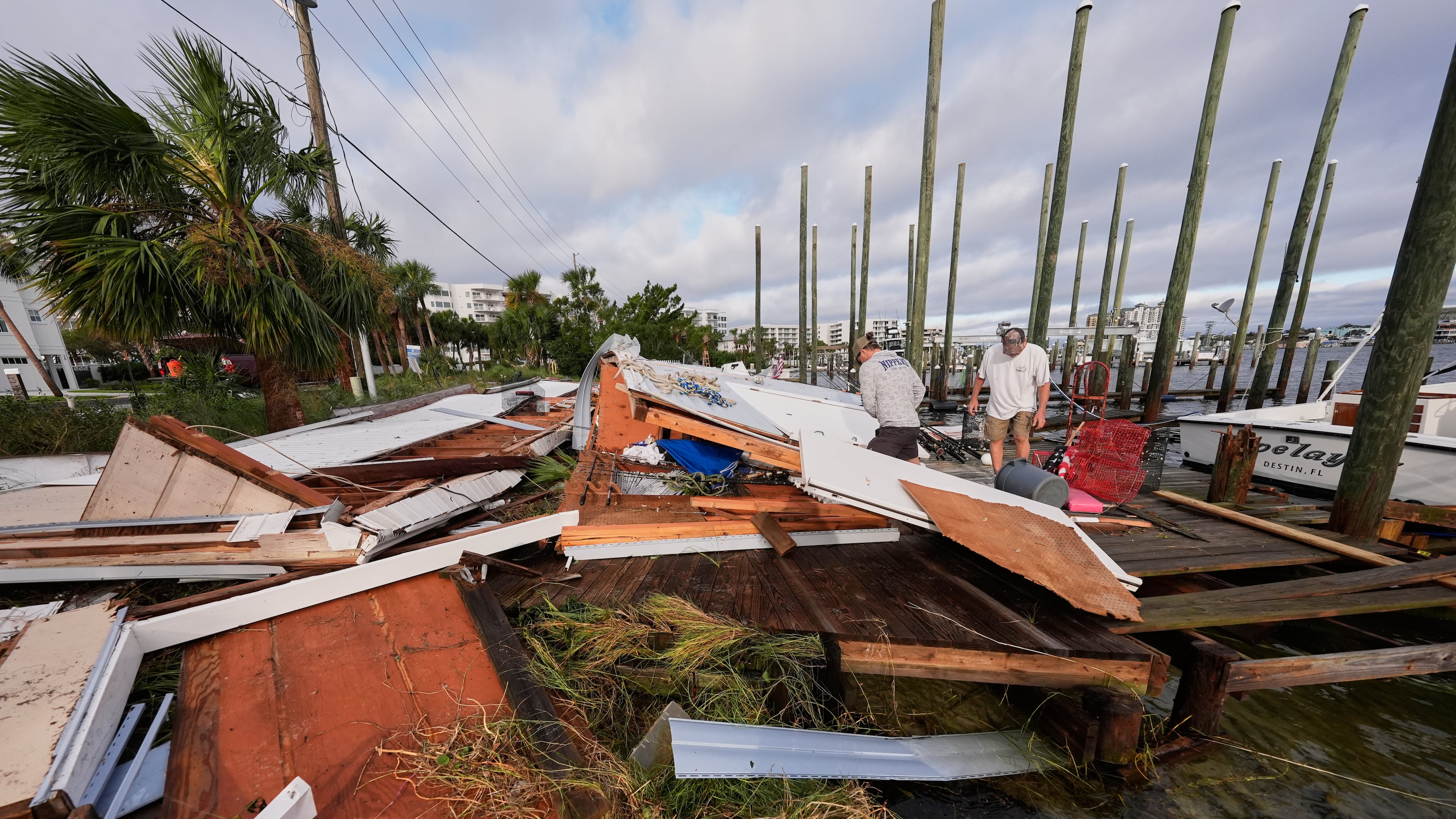 People retrieve belongings from a collapsed boat house in the aftermath of Hurricane Isaias in Destin, Fla., Saturday, Oct. 10, 2026. (AP Photo/Gerald Herbert)