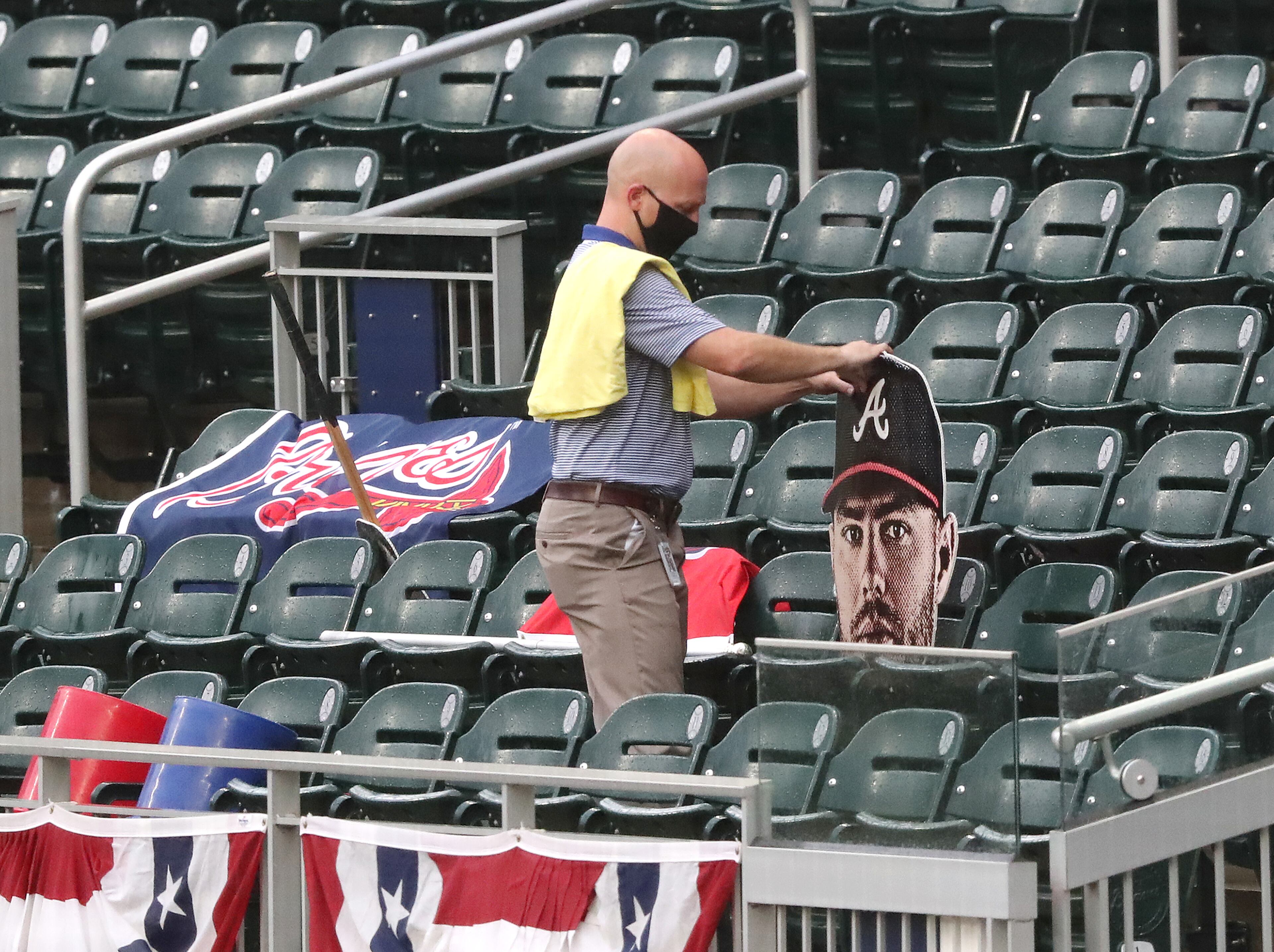 An employee sets out Braves banners and a cutout head of Freddie Freeman to help fill the empty seats at Truist Park before an exhibition against the and Marlins on Tuesday, July 21, 2020 in Atlanta. Curtis Compton ccompton@ajc.com