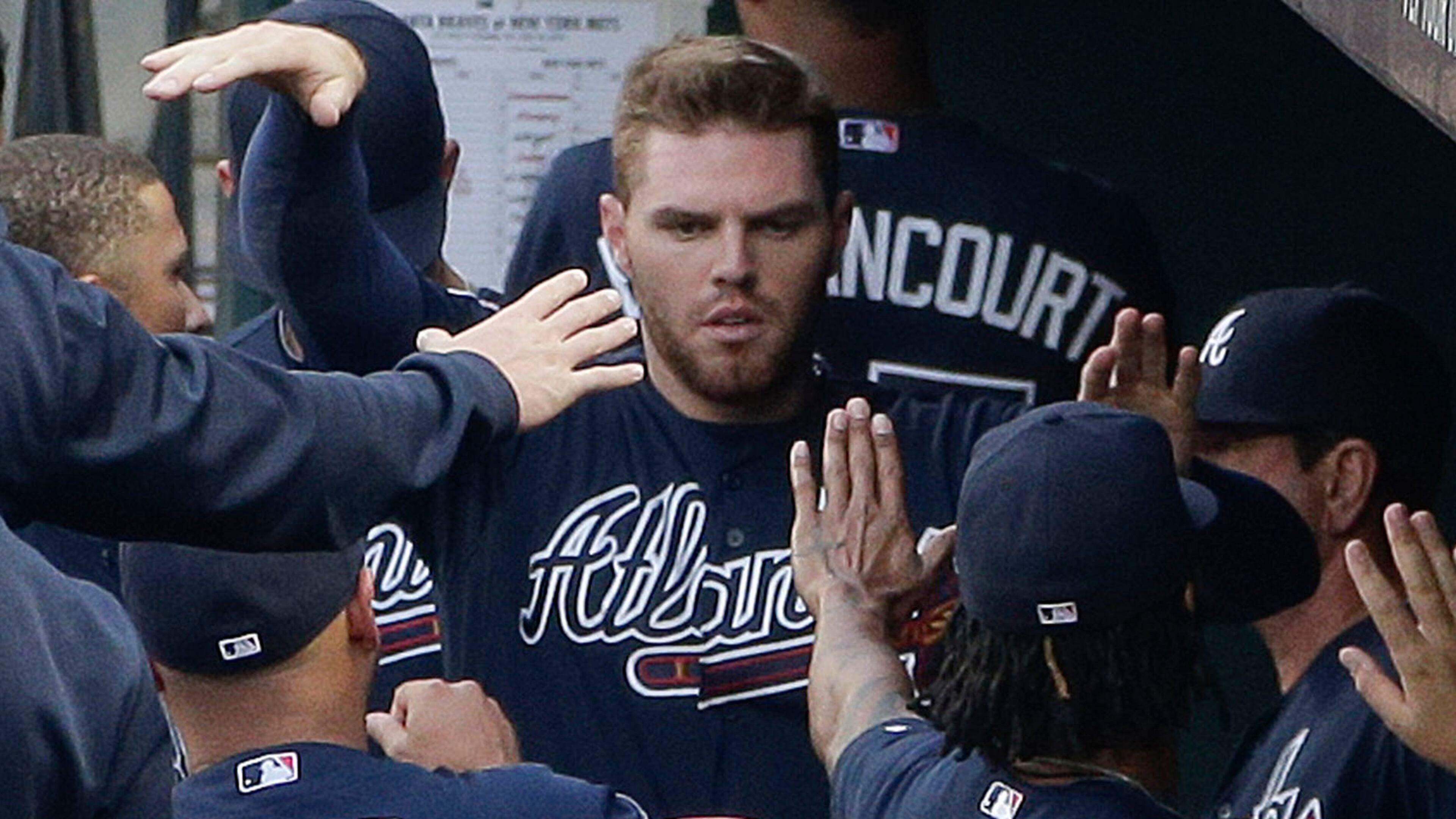 Atlanta Braves' Freddie Freeman (5) is greeted by teammates in the dugout after scoring against the New York Mets in the first inning of a baseball game, Thursday, July 10, 2014, in New York. (AP Photo/Julie Jacobson)