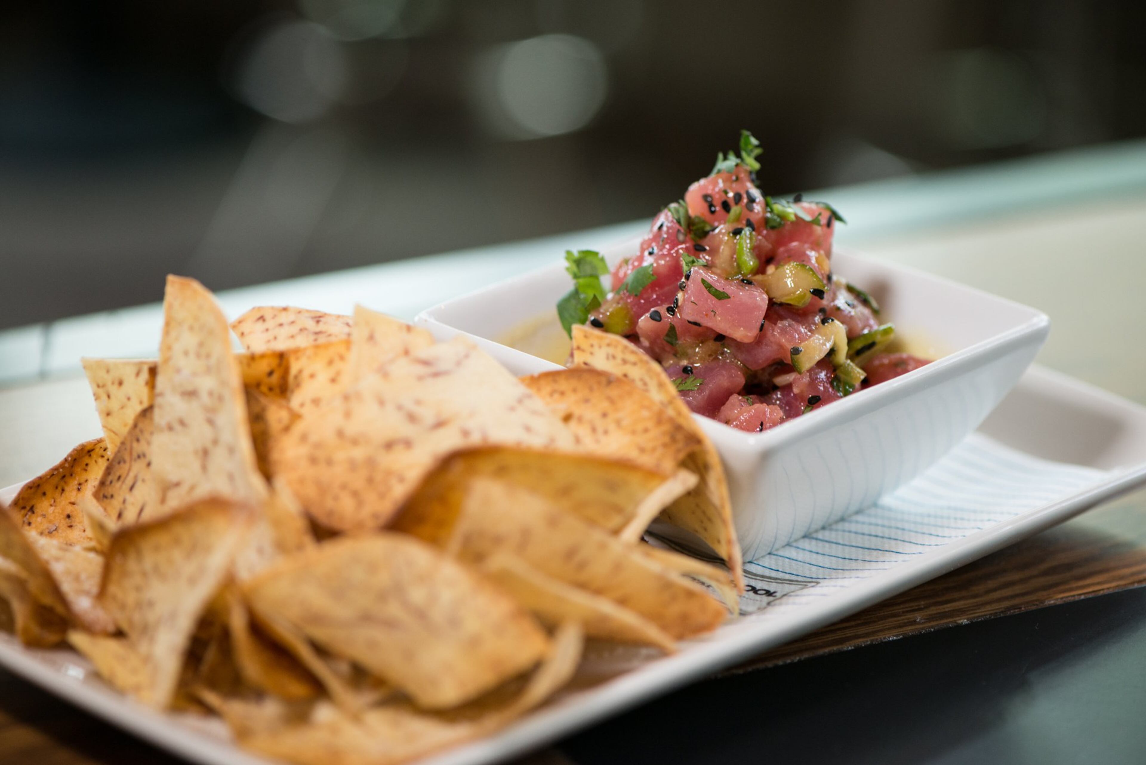 Ahi Tuna Poke with pickled cucumber, cilantro, green onion, passion fruit, and taro chips. Photo credit- Mia Yakel.