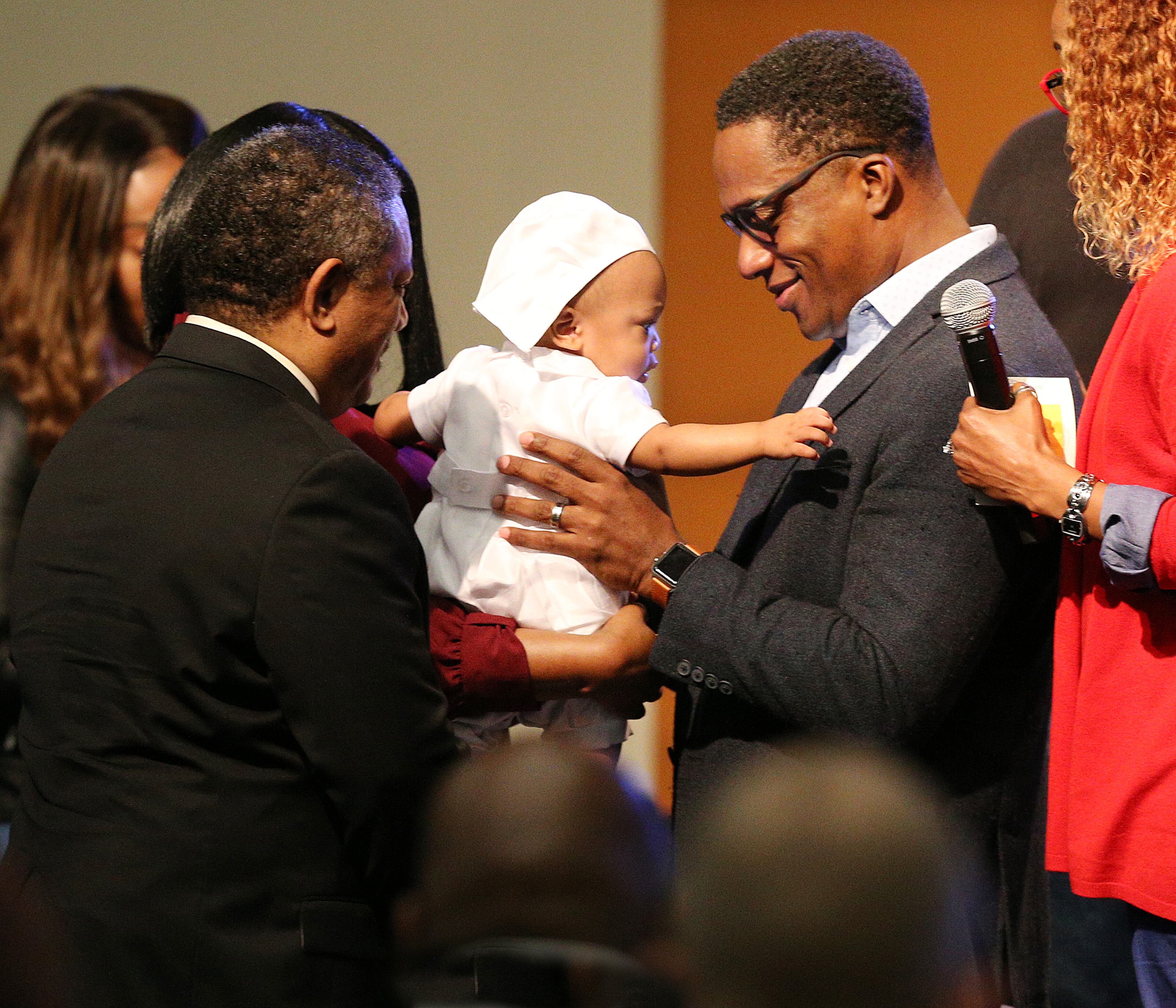 March 15, 2020 Austell: Pastor Wilbur Purvis III (right) dedicates infant Michael Kirkland to the Lord while preaching on the coronavirus saying âdonât let coronavirus steal your praiseâ during worship service at Destiny World Church on Sunday, March 15, 2020, in Austell. The congregation took a special offering to adopt a local apartment complex to supply lunch to needy school children the next two weeks. Curtis Compton ccompton@ajc.com