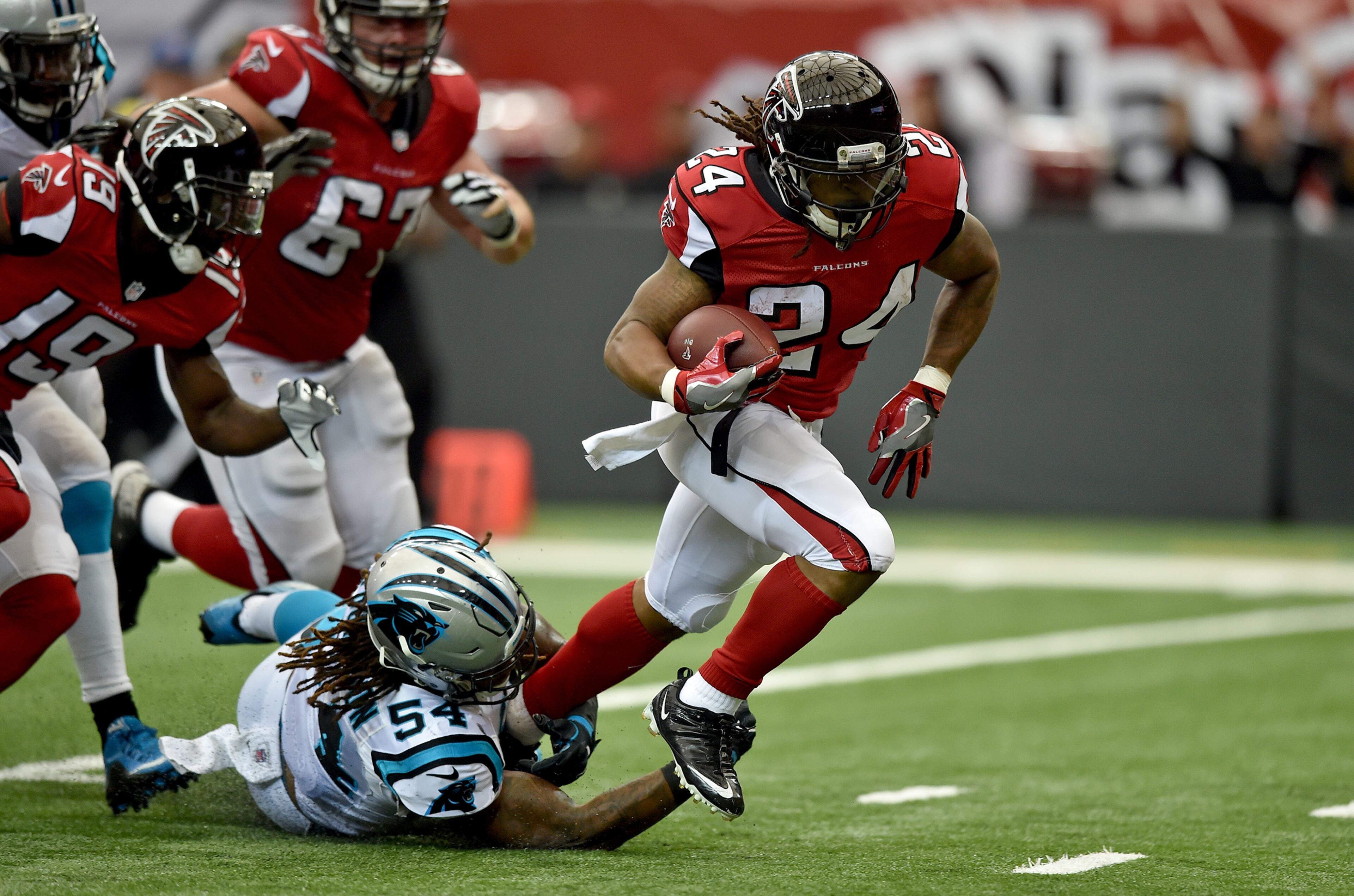 Devonta Freeman breaks the tackle of Panthers outside linebacker Shaq Green-Thompson en route to a first-quarter touchdown.