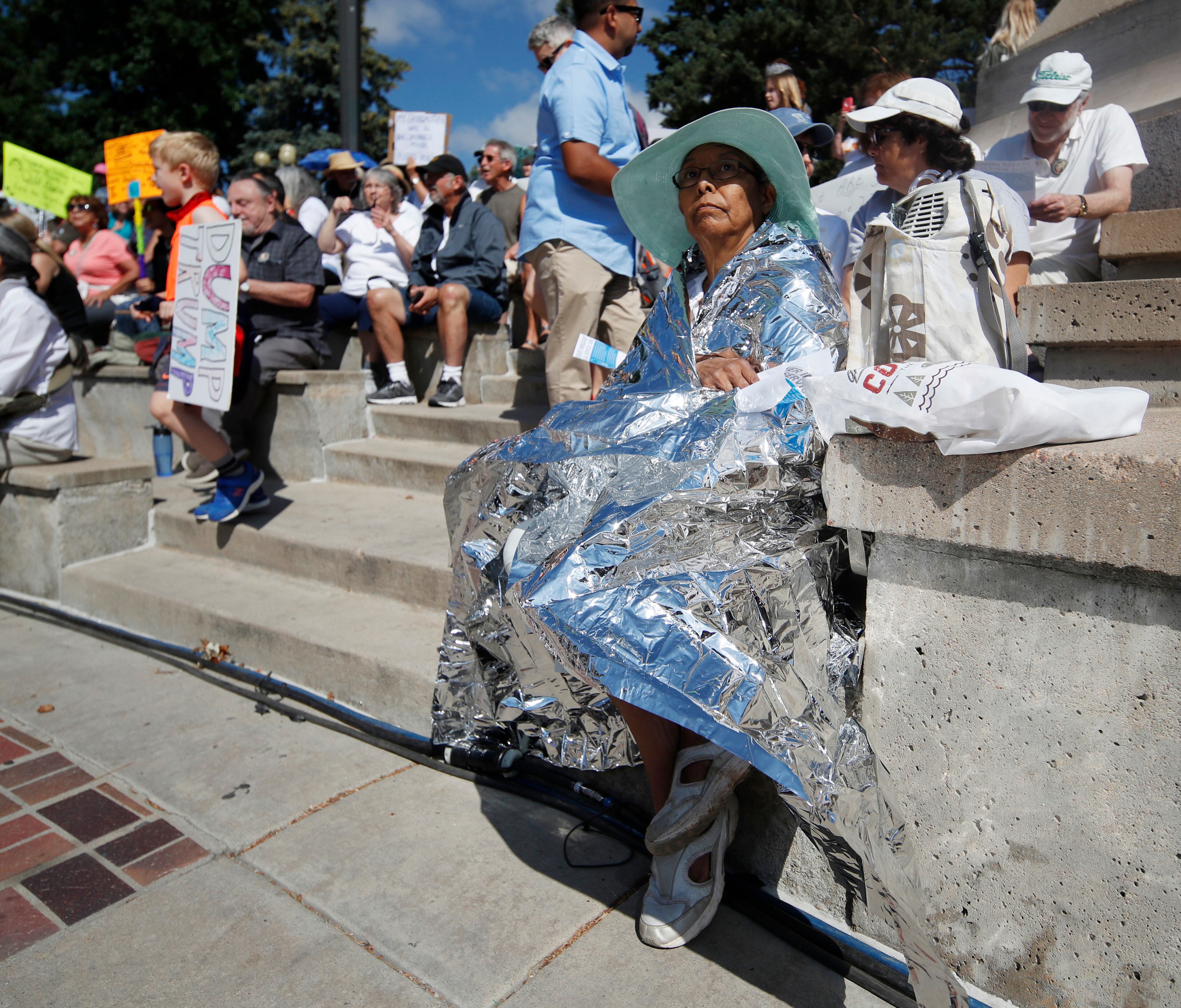 Rachel Olivarez-Sellers of Denver dons a thermal blanket during an immigration rally and protest in Civic Center Park Saturday, June 30, 2018, in downtown Denver. (AP Photo/David Zalubowski)