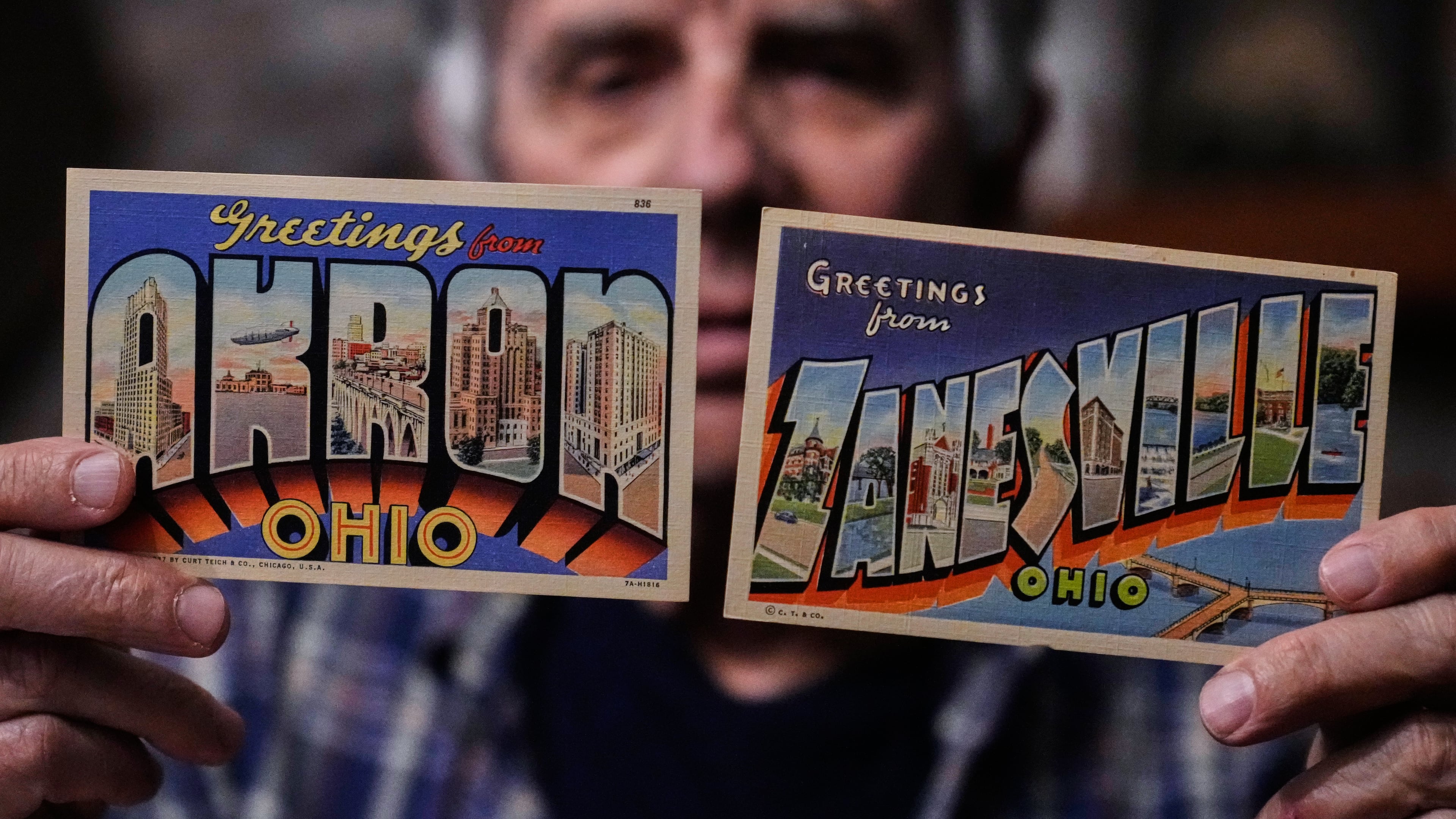 Postcard collector Peter Meggison, holds up two examples of large letter postcards from places across America going from A to Z, Akron to Zanesville, Monday, May 11, 2026, in Westport, Mass. (AP Photo/Charles Krupa)