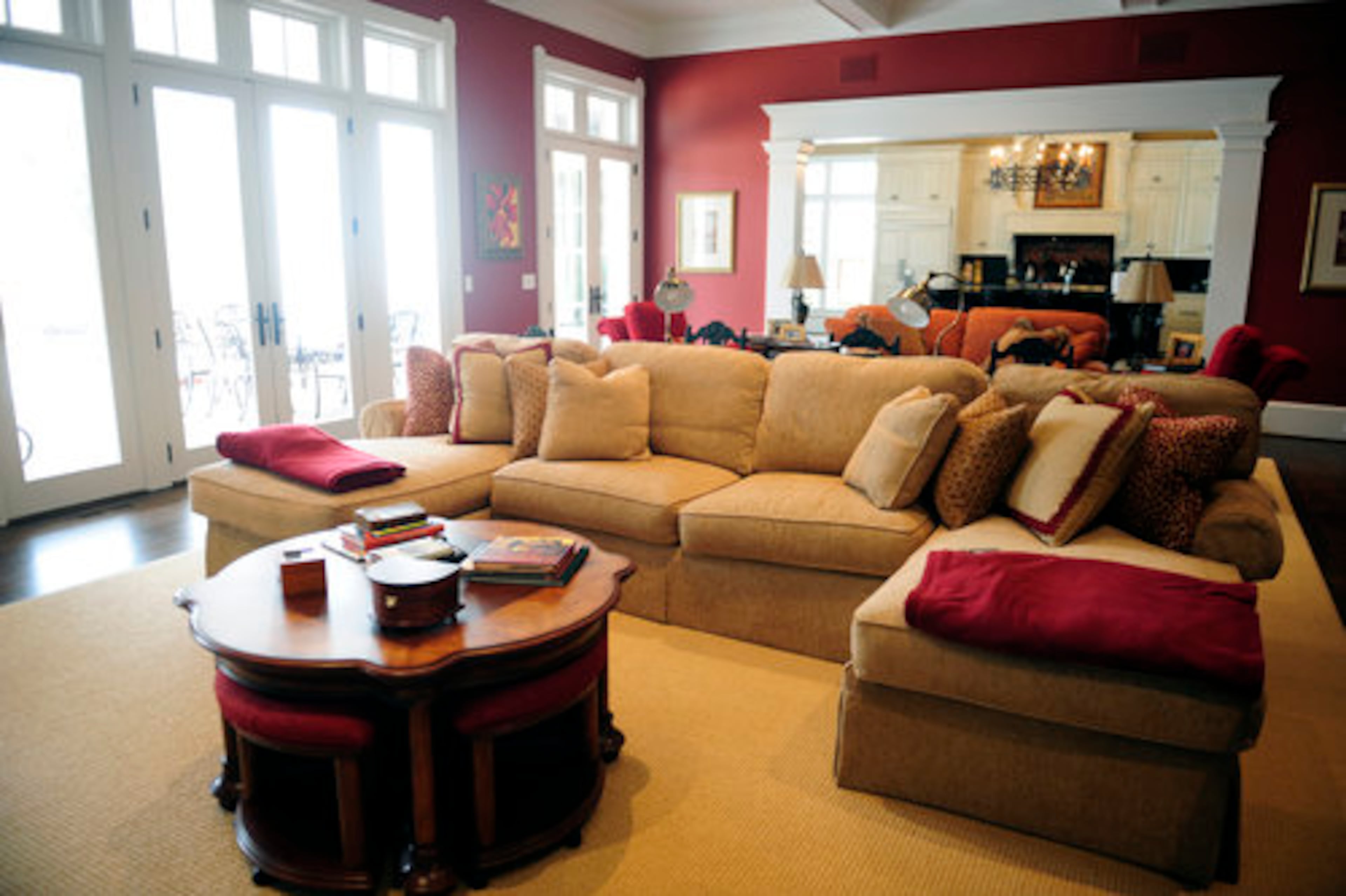 The family often assembles in the great room, which is spacious with plenty of seating. Marie's grandmother's dining table, which she had painted black, separates the seating areas. It functions as a console but can change into a dining area by using the chairs tucked beneath. Even the coffee table converts into a dining table with miniature stools. The couple chose to decorate in the "jewel tones" of gold, green and red that Marie loves. Interior designer Kimberly Davis helped them.