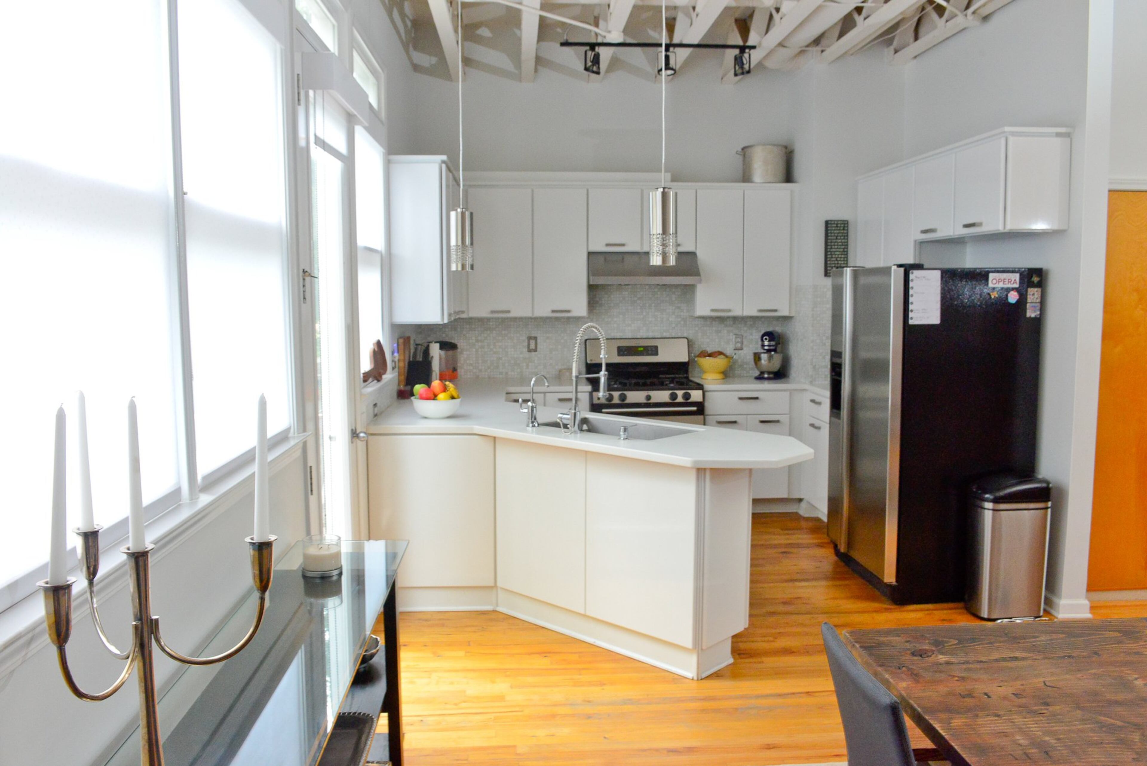 Cabinets painted white with an eggshell finish (using Behr paint) create a clean look in the loft’s kitchen. Pendant lights and stainless steel appliances give it a modern touch.