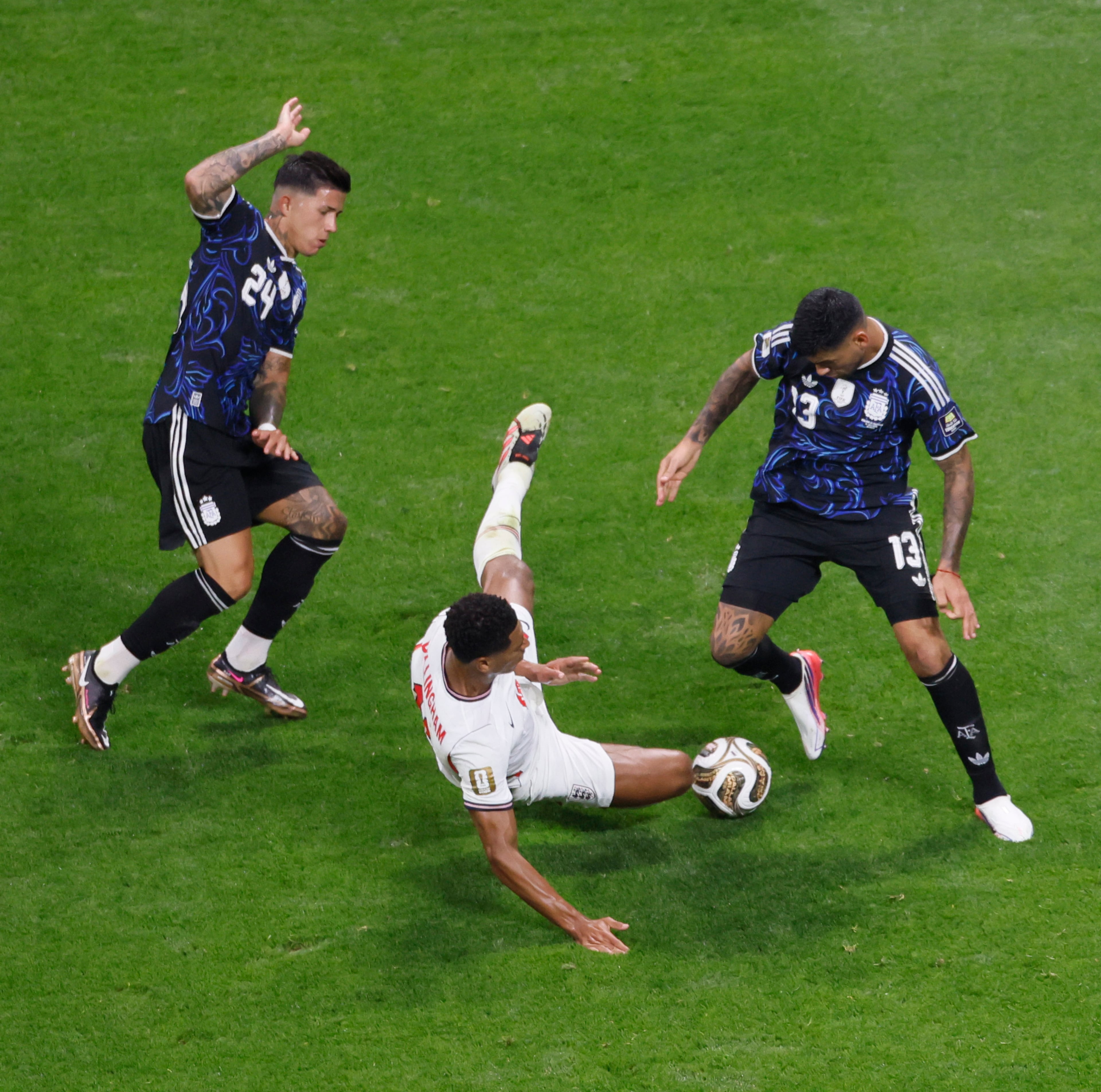England's Jude Bellingham hits the ground between Argentina's Enzo Fernandez, left and Argentina's Cristian Romero during first half of Argentina vs. England FIFA World Cup Semifinal match at Atlanta Stadium (Mercedes-Benz Stadium) on Wednesday, July 15, 2026. (Miguel Martinez/AJC)