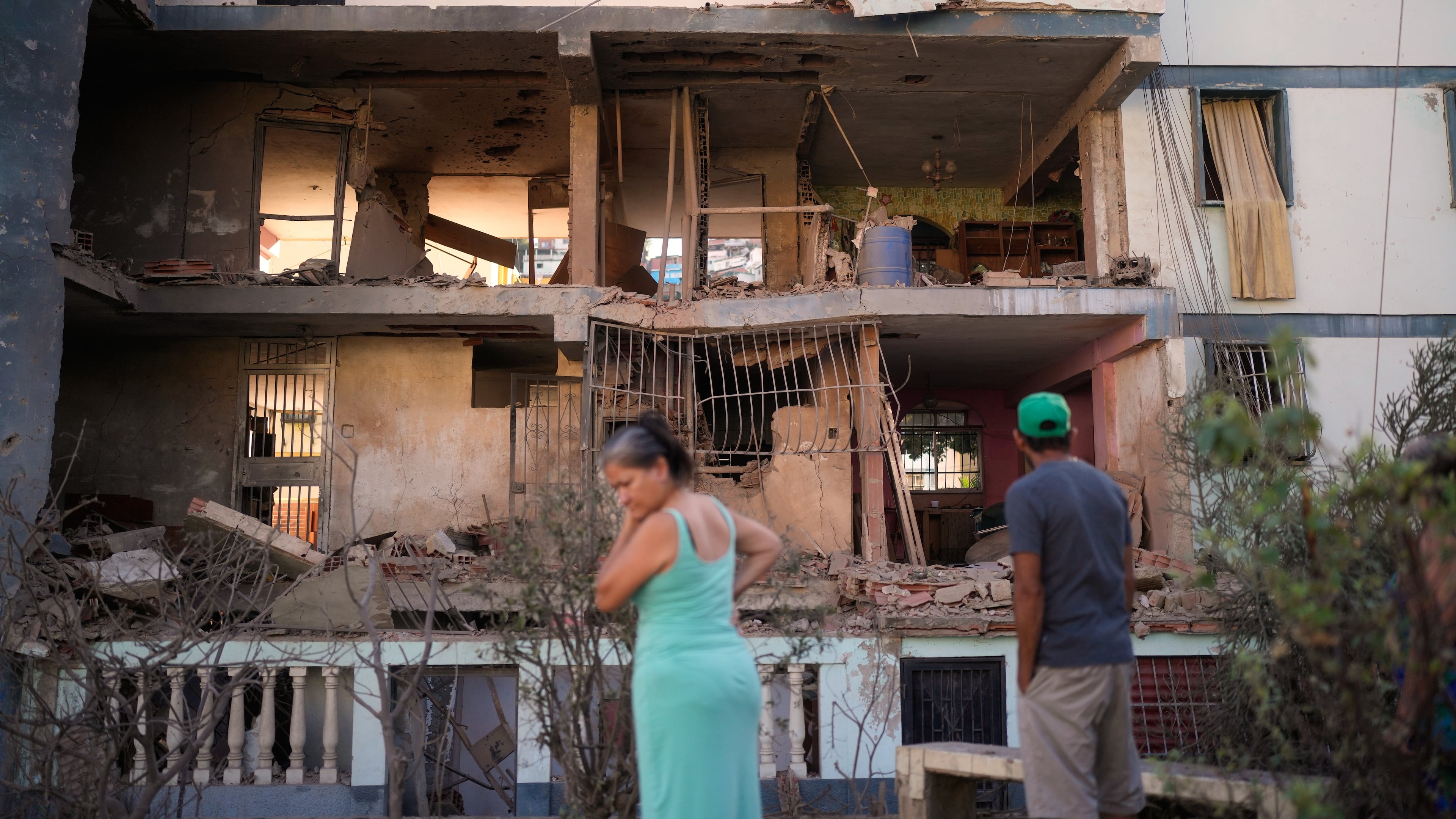 Residents look at a damaged apartment complex that neighbors say was hit during U.S. strikes to capture Venezuelan President Nicolás Maduro, in Catia La Mar, Venezuela, Sunday, Jan. 4, 2026. (AP Photo/Matias Delacroix)