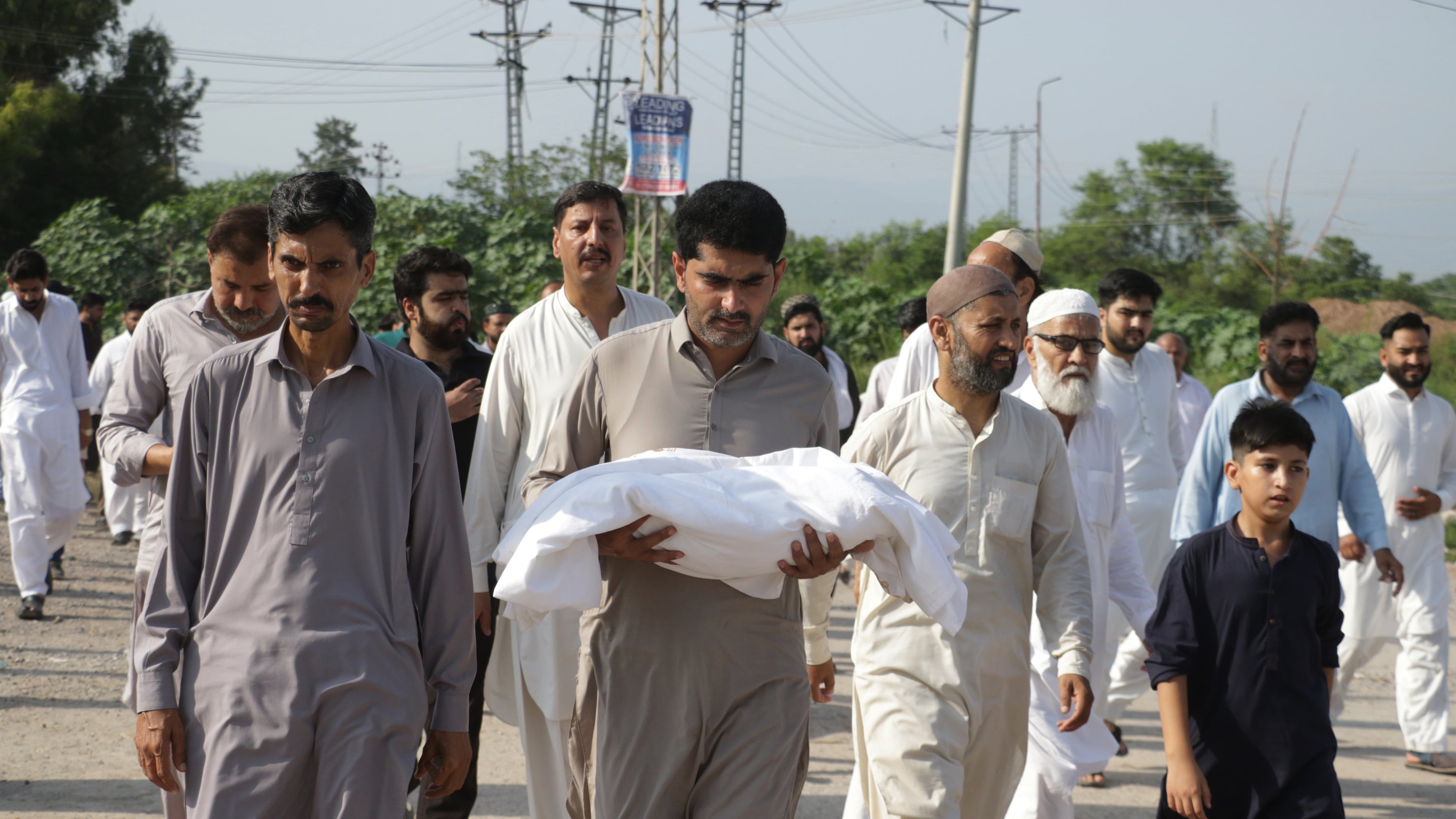 A man carries the body of a newborn for burial after the child died in a fire at a hospital in Islamabad, Pakistan, Wednesday, Aug. 26, 2026. (AP Photo/Ehsan Shahzad)