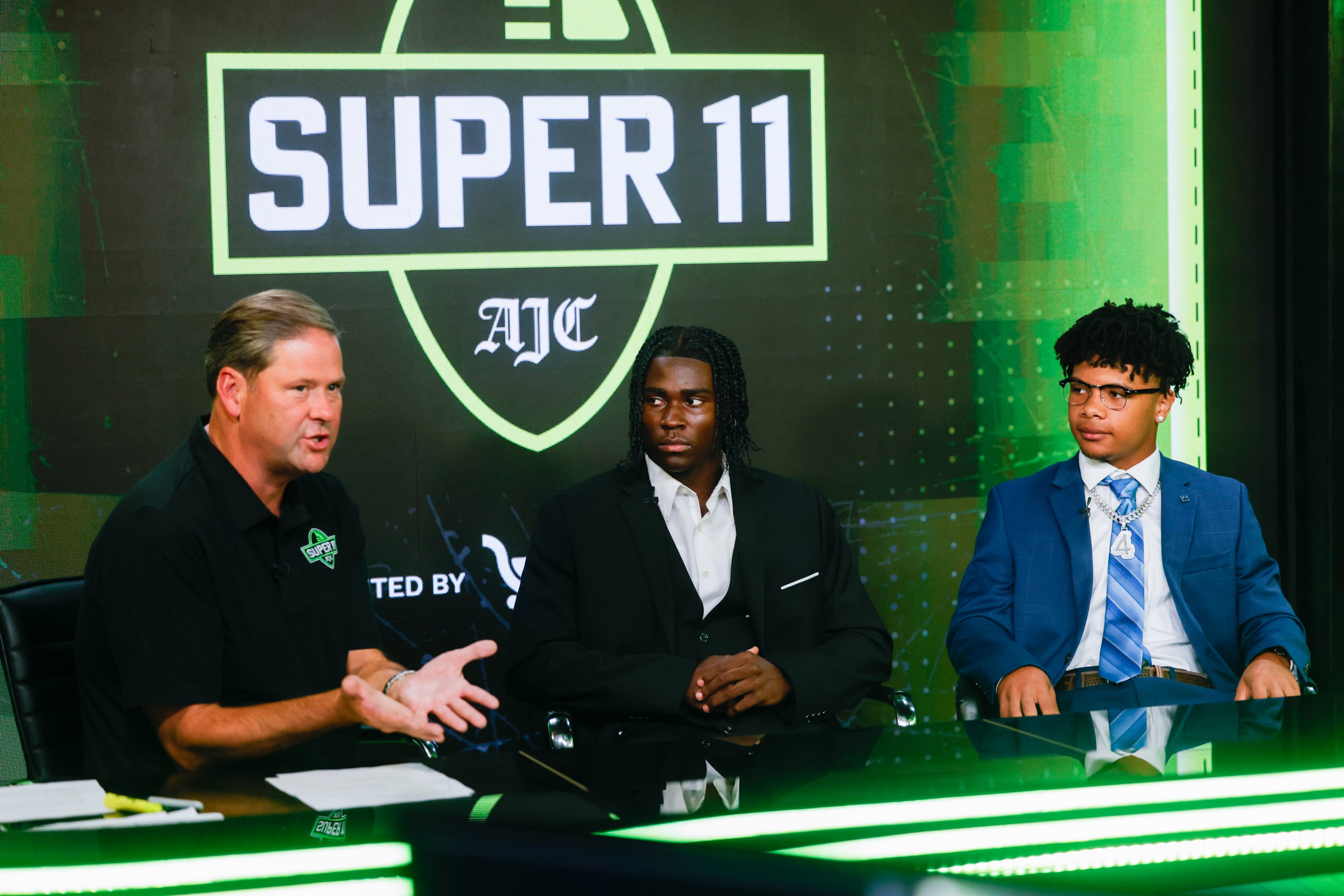 (L-R) DawgNation’s Brandon Adams interviews Creekside’s Gary Walker and Valdosta’s Marquis Fennell during the taping of the Super 11 reveal show at Score ATL in Roswell on Aug. 3, 2026. (Arvin Temkar/AJC)