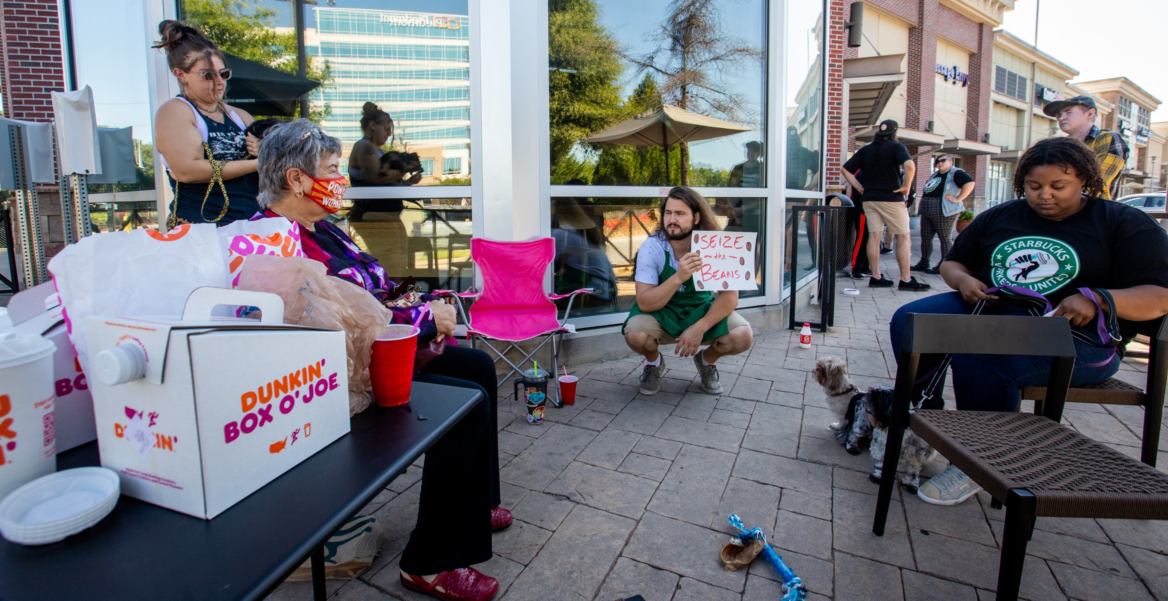 Starbucks employees, union workers, labor activists and former Starbucks employees, picket at the Howell Mill location with coffee from Dunkin’ Donuts while on strike Sunday, July 17, 2022 after voting to join the union and asking for guaranteed work hours, benefits and a contract to protect the hourly workers. Starbucks management has not responded to requests to start negotiation. (Jenni Girtman for The Atlanta Journal-Constitution)