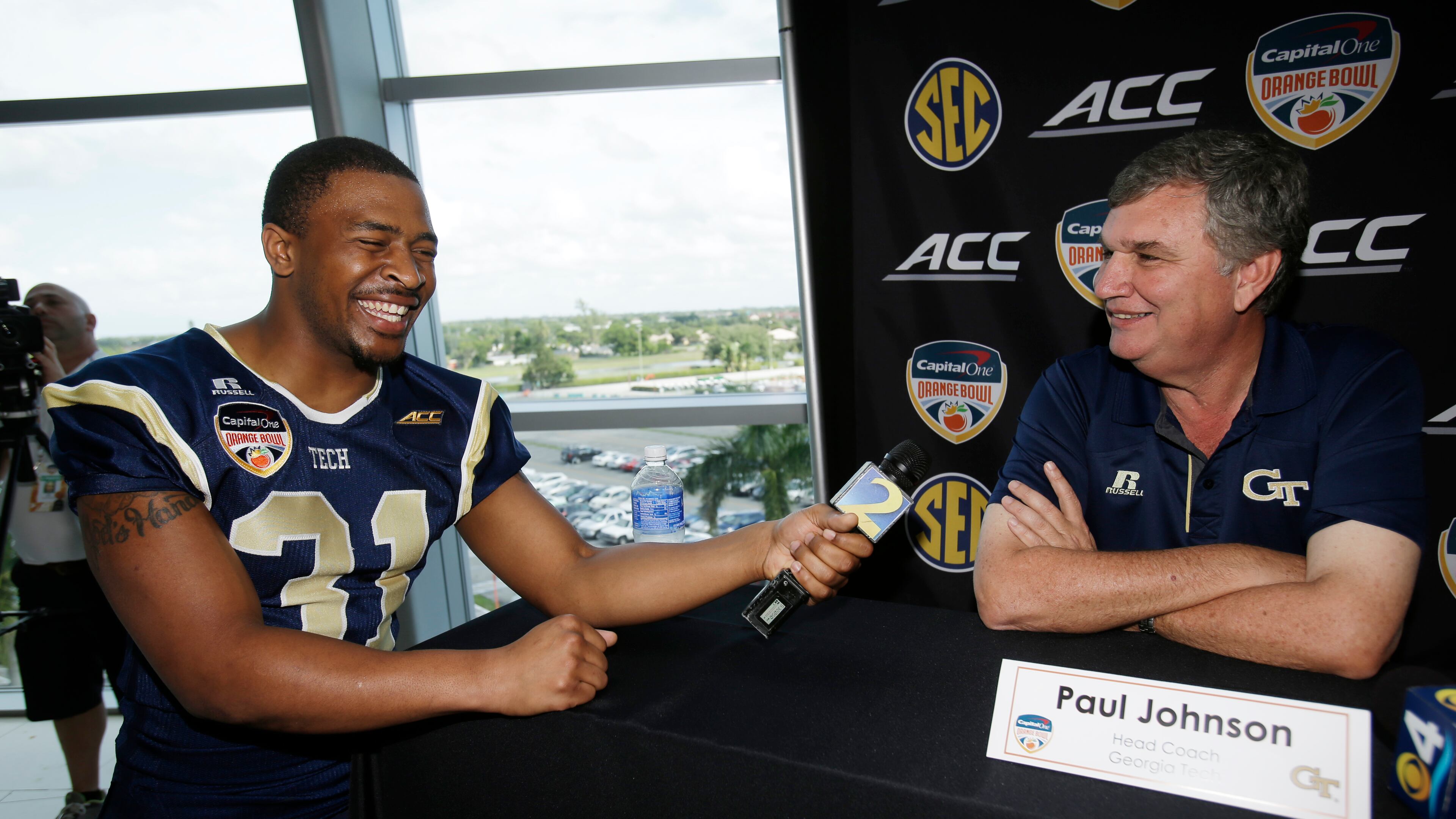 Georgia Tech running back Deon Hill, left, laughs after head coach Paul Johnson answered his question during media day, Monday, Dec. 29, 2014, in Miami Gardens, Fla. Georgia Tech will play Mississippi State in the Orange Bowl NCAA college football game on New Year's Eve. (AP Photo/Wilfredo Lee). Georgia Tech A-back Deon Hill demands answers from coach Paul Johnson during the team's media day appearance at Sun Life Stadium. (ASSOCIATED PRESS)