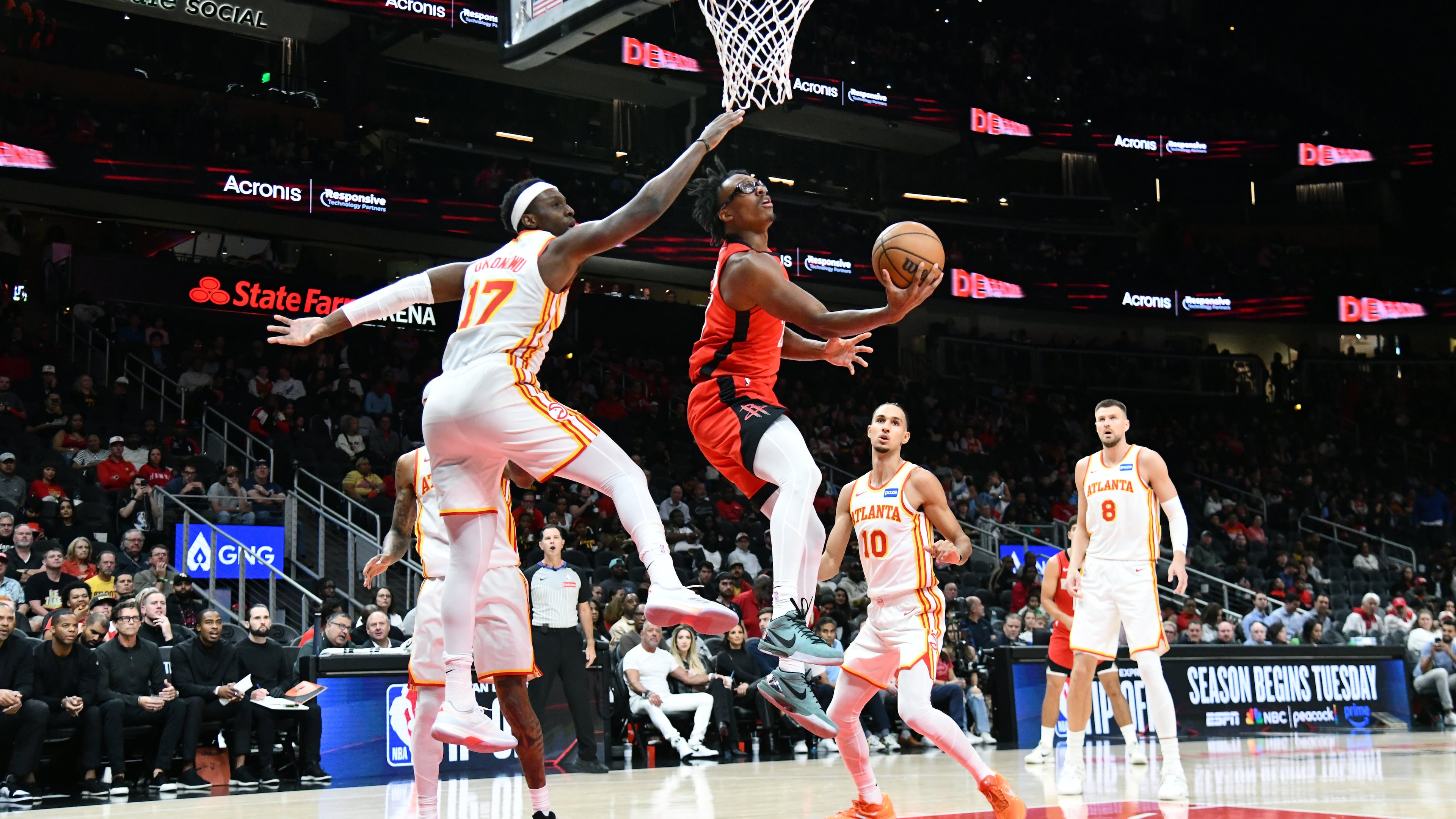 Houston Rockets forward Isaiah Crawford (center) goes to the basket for the shot against Atlanta Hawks forward/center Onyeka Okongwu (left) during the first half in a preseason NBA basketball game at State Farm Arena, Thursday, Oct. 16, 2025, in Atlanta. (Hyosub Shin/AJC)