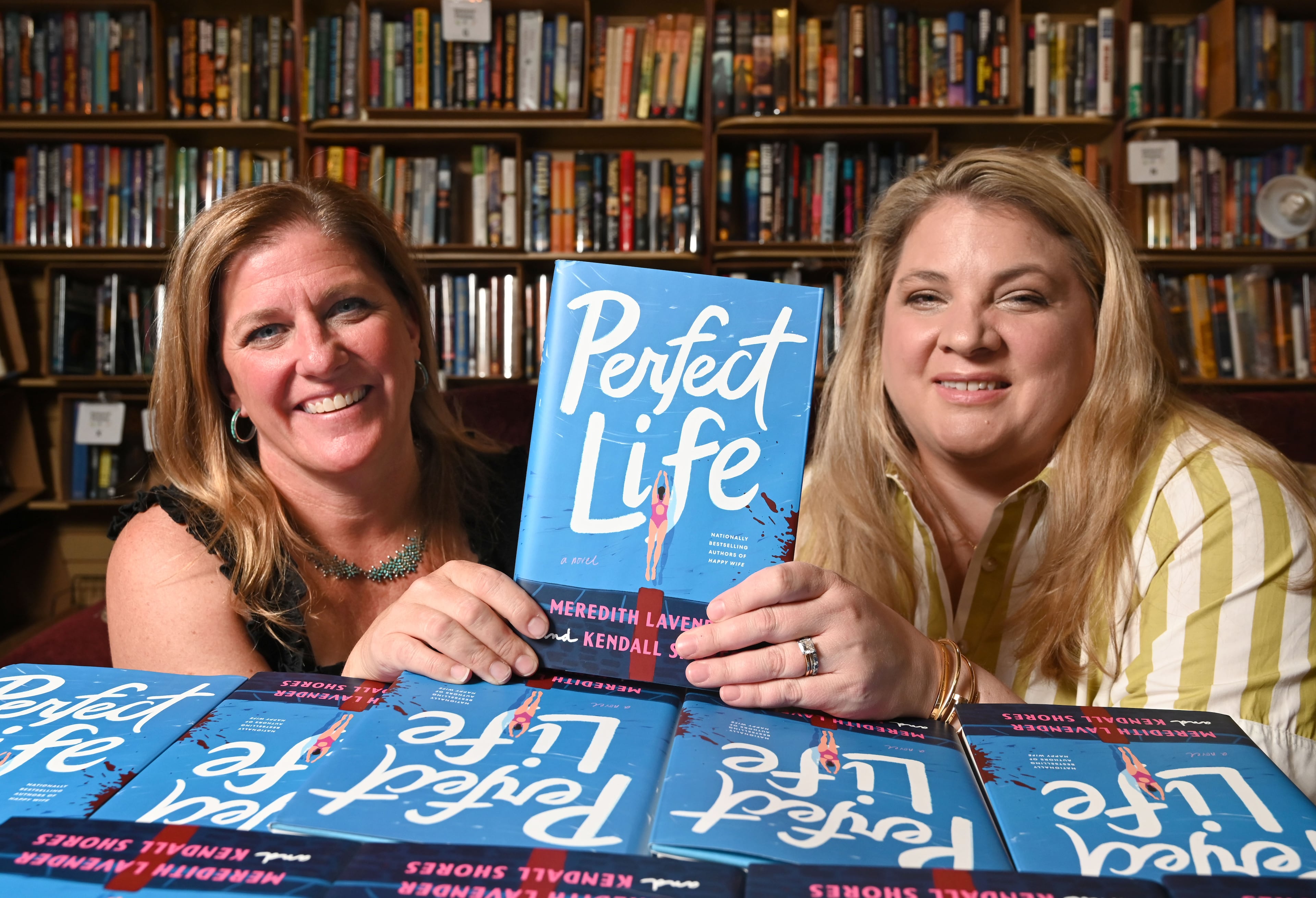 Meredith Lavender, left, and Kendall Shores, co-authors of Perfect Life, hold a copy of their book, Perfect Life, as they pose for a portrait at Eagle Eye Book Shop on Wednesday, July 8, 2026, in Decatur. (Hyosub Shin/AJC)