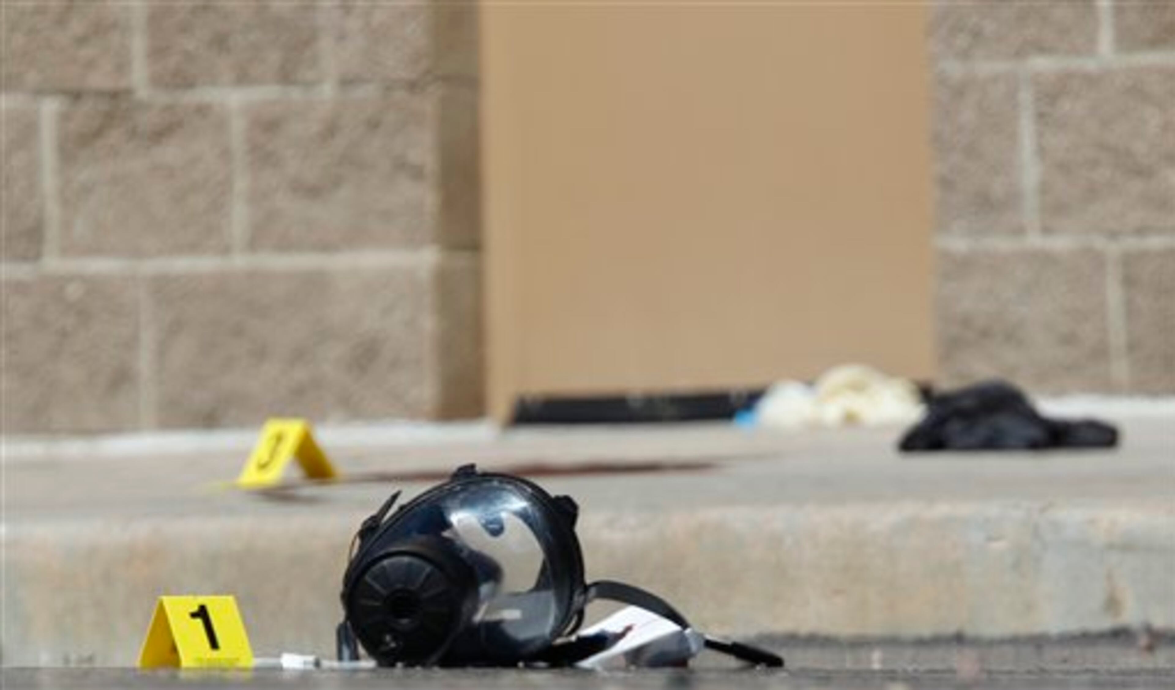 Yellow markers sit next to evidence, including a gas mask, as police investigate the scene outside the Century 16 movie theater east of the Aurora Mall in Aurora, Colo. on Friday, July 20, 2012. A gunman in a gas mask barged into a crowded Denver-area theater during a midnight showing of the Batman movie on Friday, hurled a gas canister and then opened fire in one of the deadliest mass shootings in recent U.S. history. (AP Photo/David Zalubowski)
