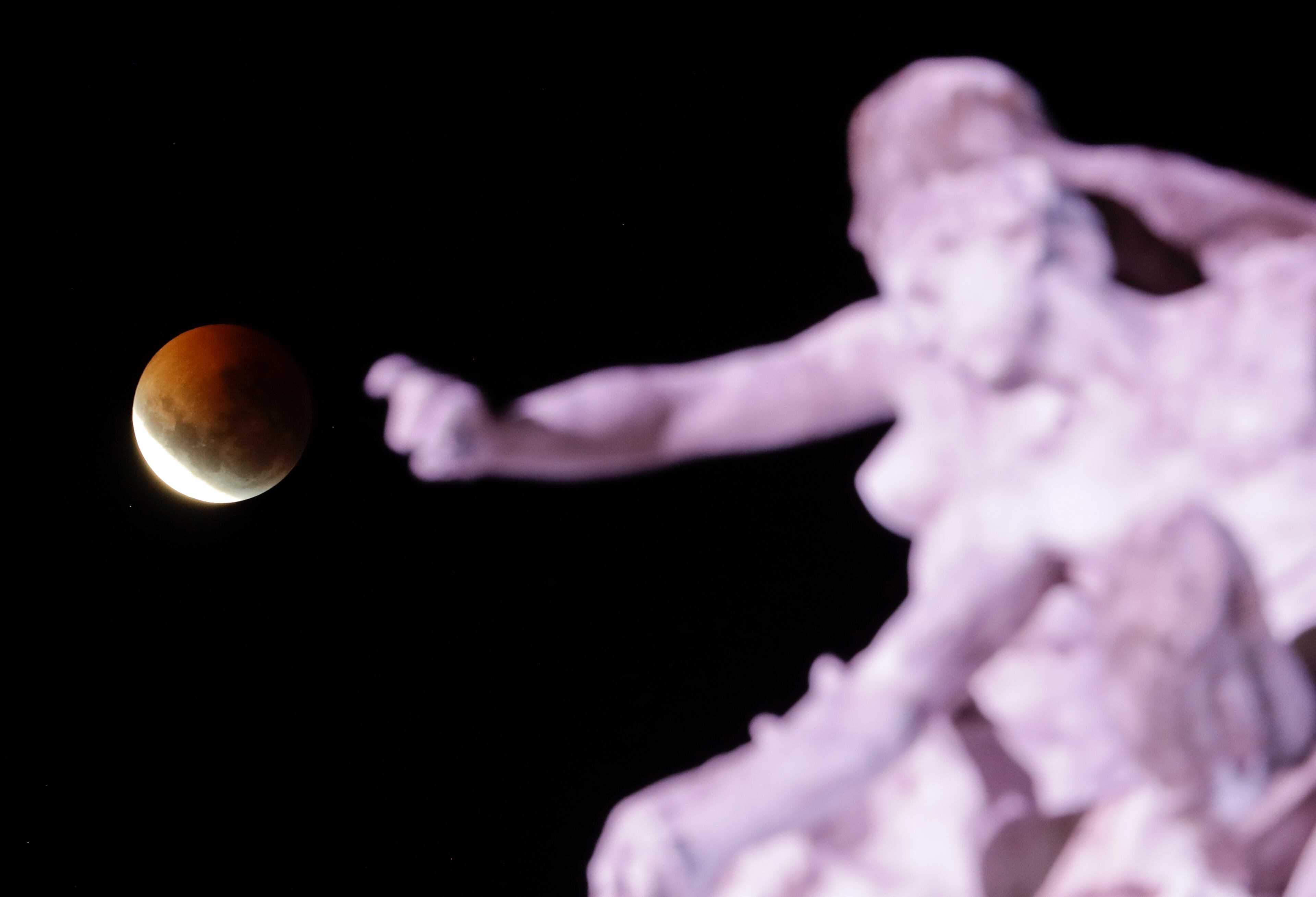 A lunar eclipse progresses behind the "Monumento a la Carta Magna y Las Cuatro Regiones Argentinas" in Buenos Aires, Argentina, Monday, Jan. 21, 2019. It's also the year's first supermoon, when a full moon appears a little bigger and brighter thanks to its slightly closer position to Earth. (AP Photo/Natacha Pisarenko)
