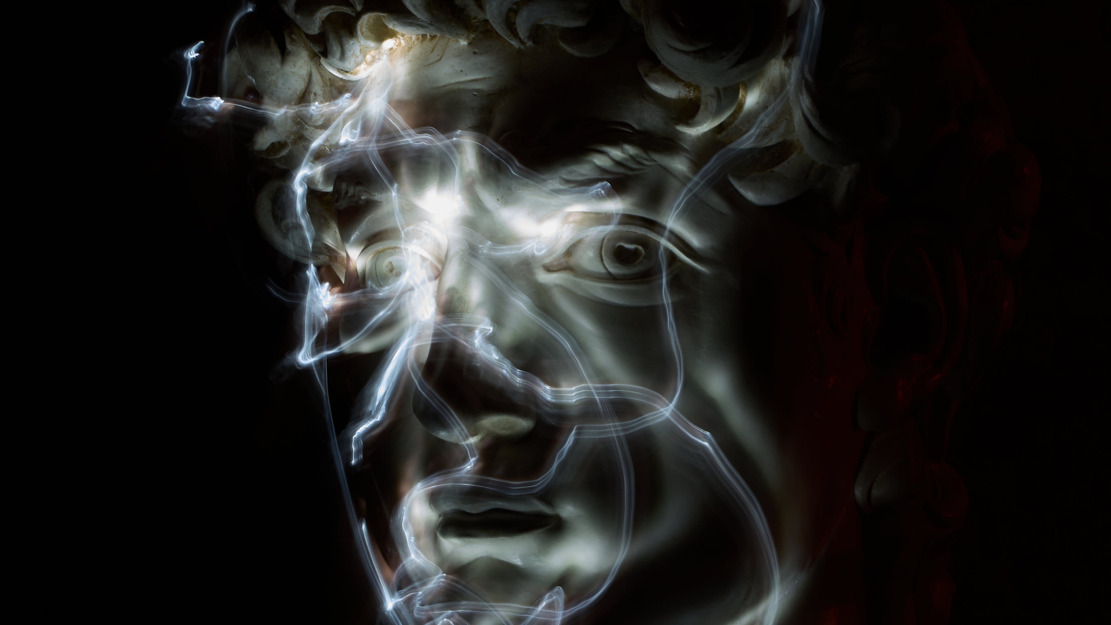 Stefania Terre, who is blind, uses a small light on her fingers while touching a life-size reproduction of the head of Michelangelo's David as she poses for a long-exposure photograph at the Omero Tactile Museum in Ancona, Italy, Thursday, Jan. 15, 2026. (AP Photo/Alessandra Tarantino)