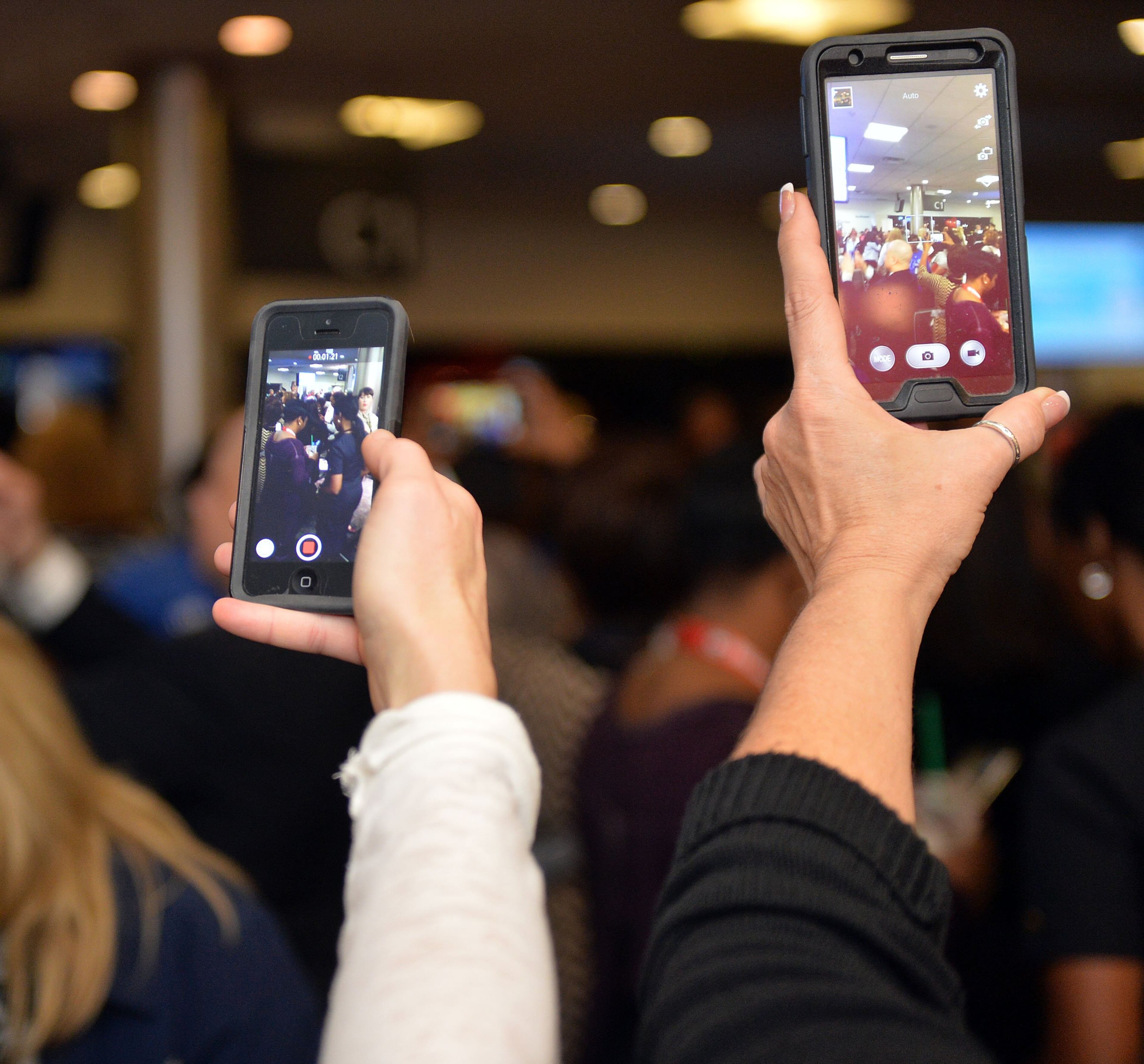 Former flight attendants Tara Cortes and Suzanne Wayda record the event. Hundreds of Southwest Airlines and former AirTran Airways employees gathered at Concourse C, gates 1, 2 and 3 to celebrate the departure of AirTran’s final flight to Tampa, at Hartsfield-Jackson International Airport, Sunday, December 28, 2014. Southwest CEO Gary Kelly and executives Bob Jordan and Jack Smith gave remarks during the program. The full flight was waved off by employees that gathered on the tarmac as crash trucks from Atlanta Fire Rescue gave a final water cannon salute as the plane departed. KENT D. JOHNSON/KDJOHNSON@AJC.COM