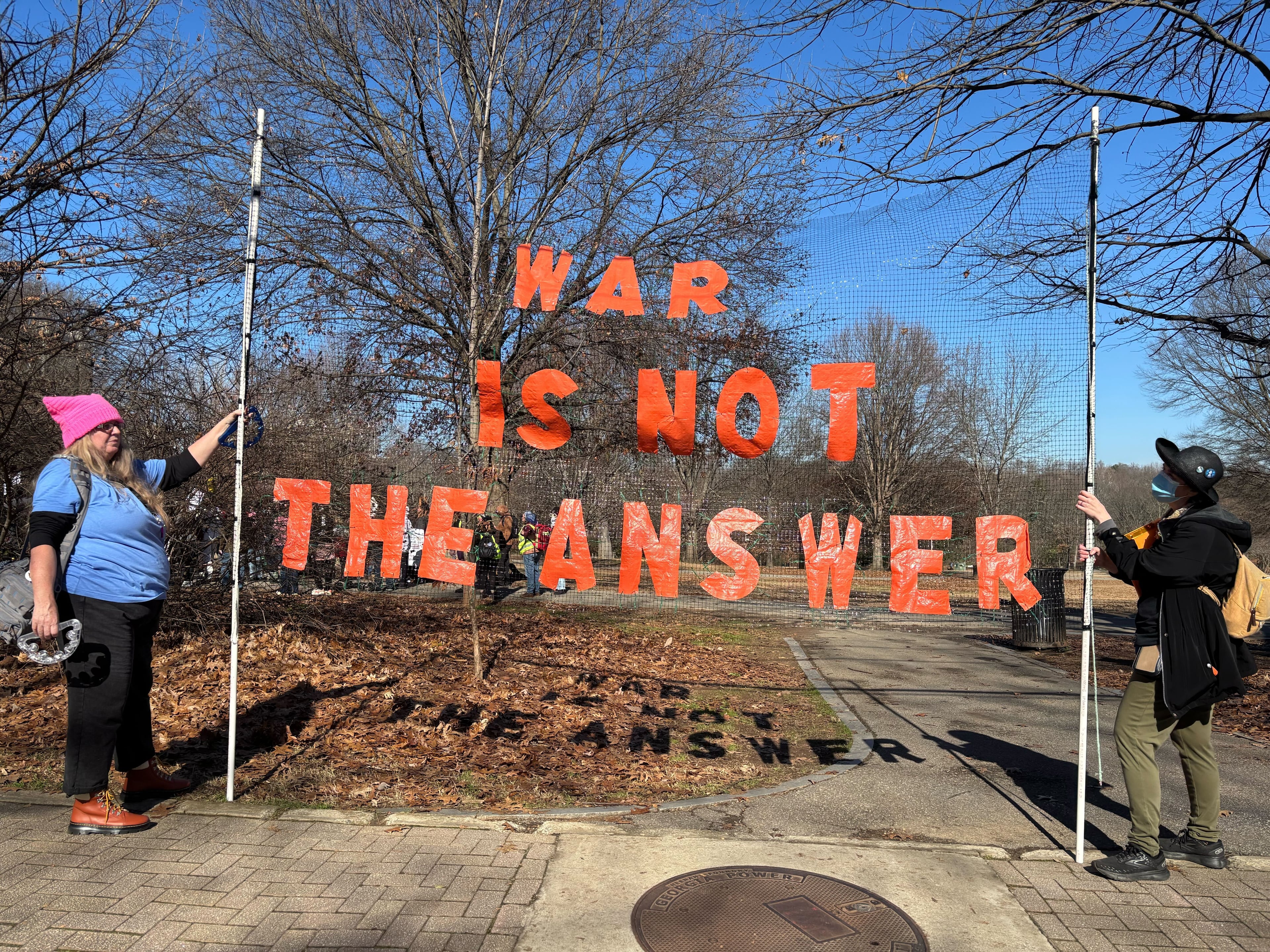 Two people hold up a large sign that reads "WAR IS NOT THE ANSWER" during a rally at Piedmont Park Sunday. (David Aaro/AJC)