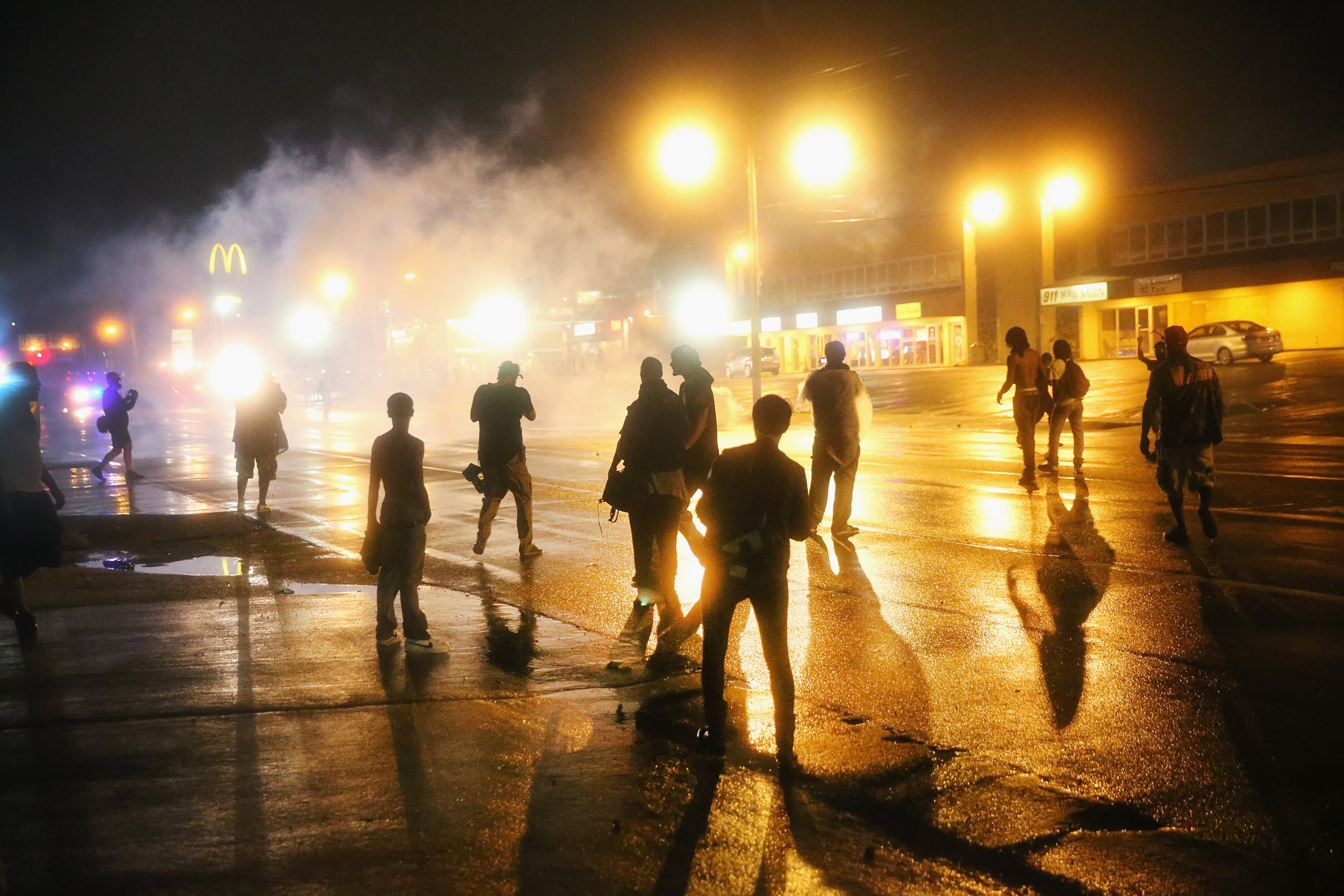 FERGUSON, MO - AUGUST 17: Police fire tear gas at demonstrators protesting the shooting of Michael Brown after they refused to honor the midnight curfew on August 17, 2014 in Ferguson, Missouri. The curfew was imposed on Saturday in an attempt to reign in the violence that has erupted nearly every night in the suburban St. Louis town since the shooting death of teenager Michael Brown by a Ferguson police officer on August 9. (Photo by Scott Olson/Getty Images)