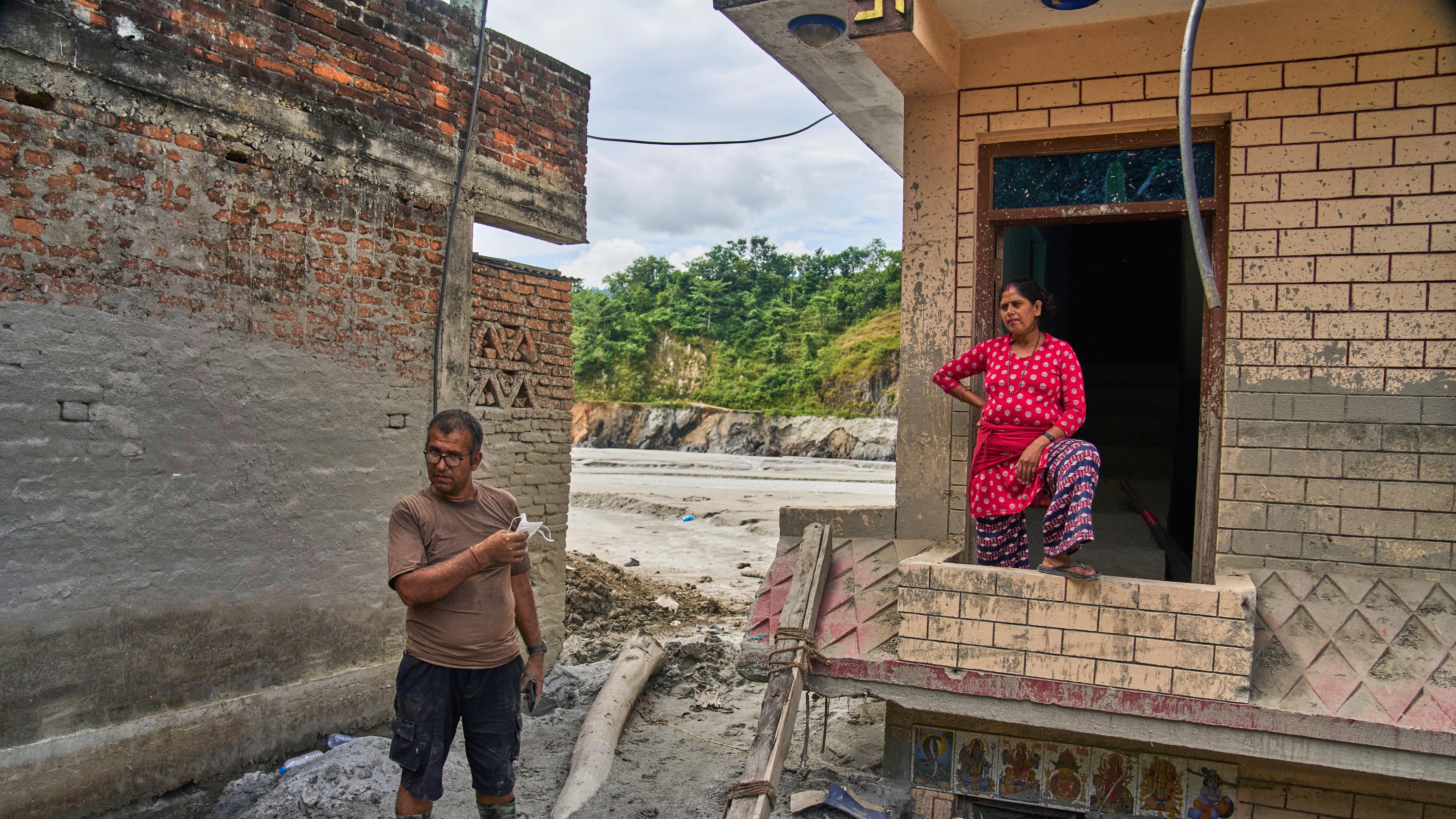 Narayan Prasad Nepal, left, stands outside his damaged house by a flash flood in Galchi, Nuwakot, Nepal, Wednesday, Sept. 23, 2026. (AP Photo/Niranjan Shrestha)