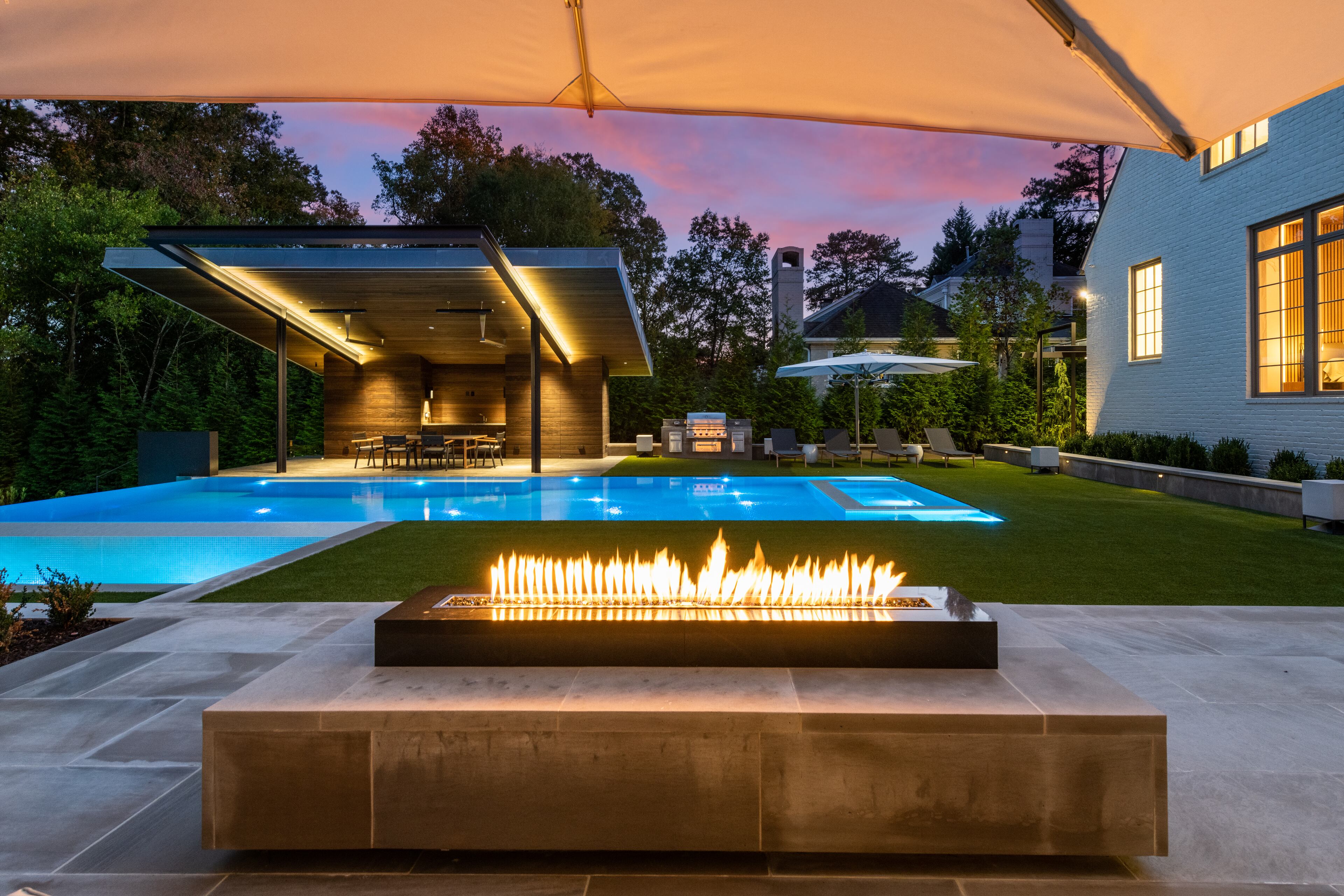 The backyard includes a pavilion, outdoor kitchen area and mounted heaters.